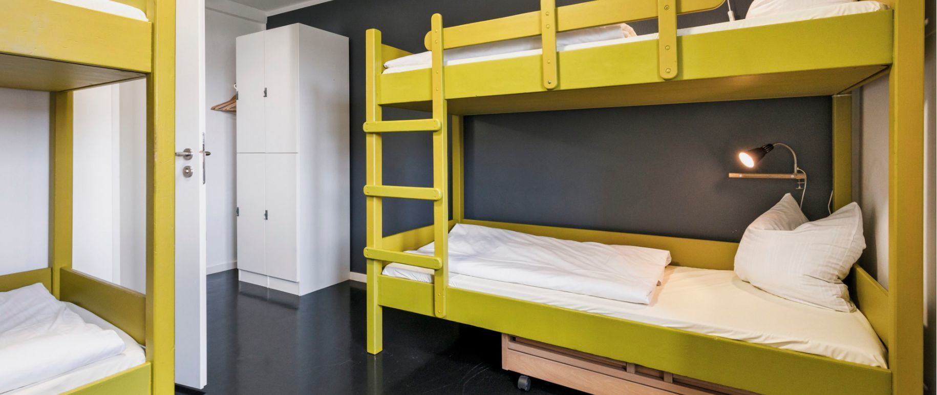 Gelbe Etagenbetten in einem Zimmer mit grauer Wand und weißen Schränken.