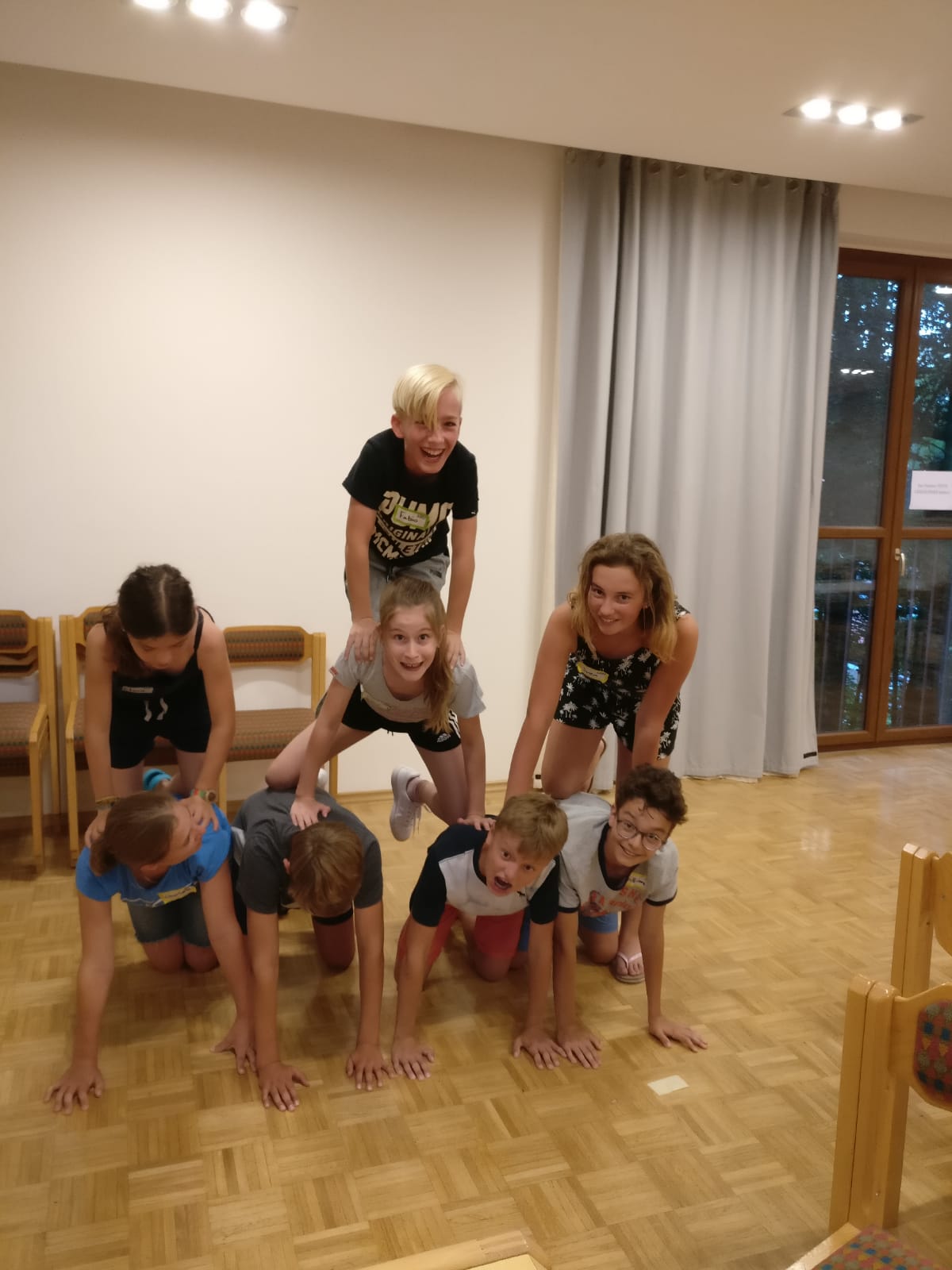 Eine Gruppe Kinder baut in einem Raum eine Pyramide.