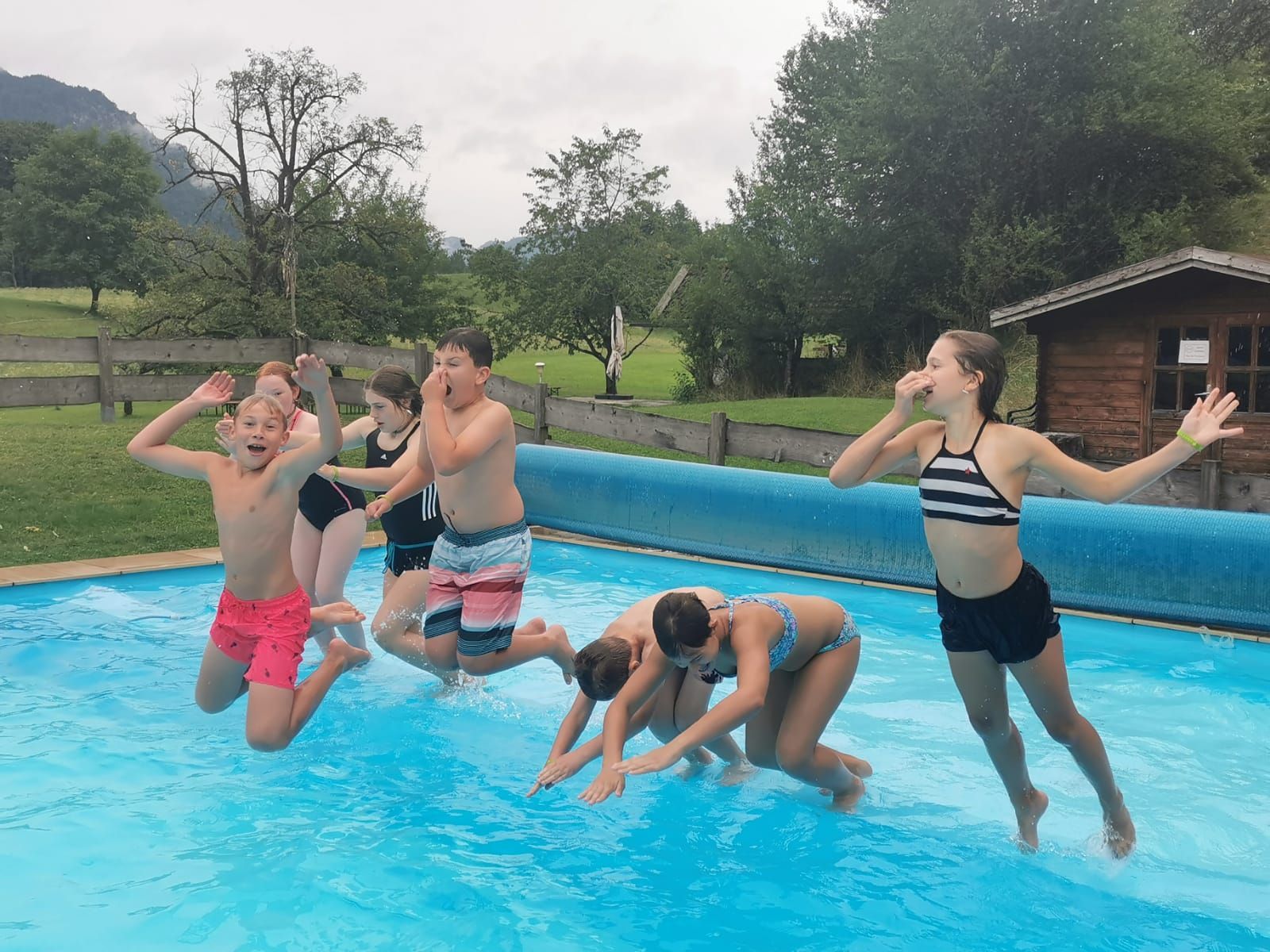 Eine Gruppe Kinder springt in ein Schwimmbad.