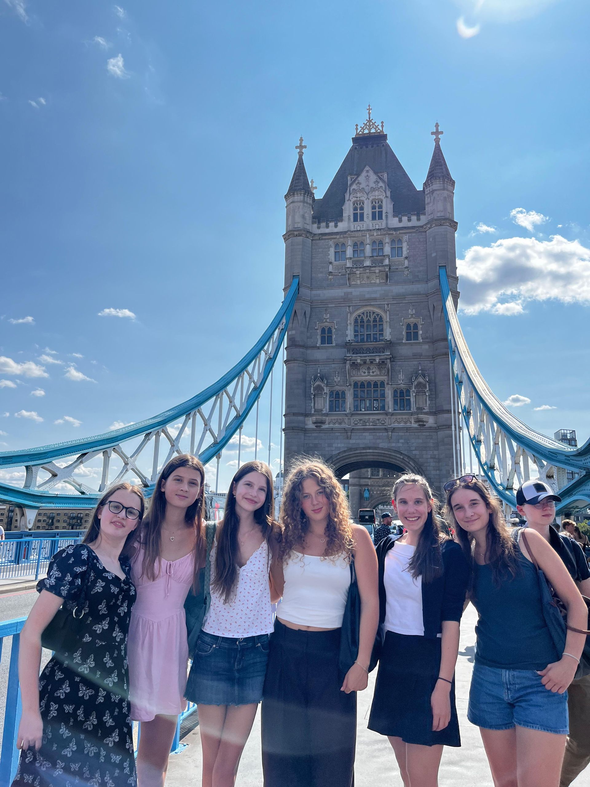 Eine Gruppe von Menschen posiert an einem sonnigen Tag auf der Tower Bridge in London.