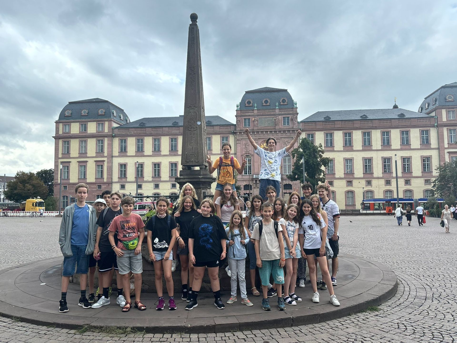 Eine Gruppe von Studenten posiert in der Nähe eines Obelisken vor einem großen Gebäude.