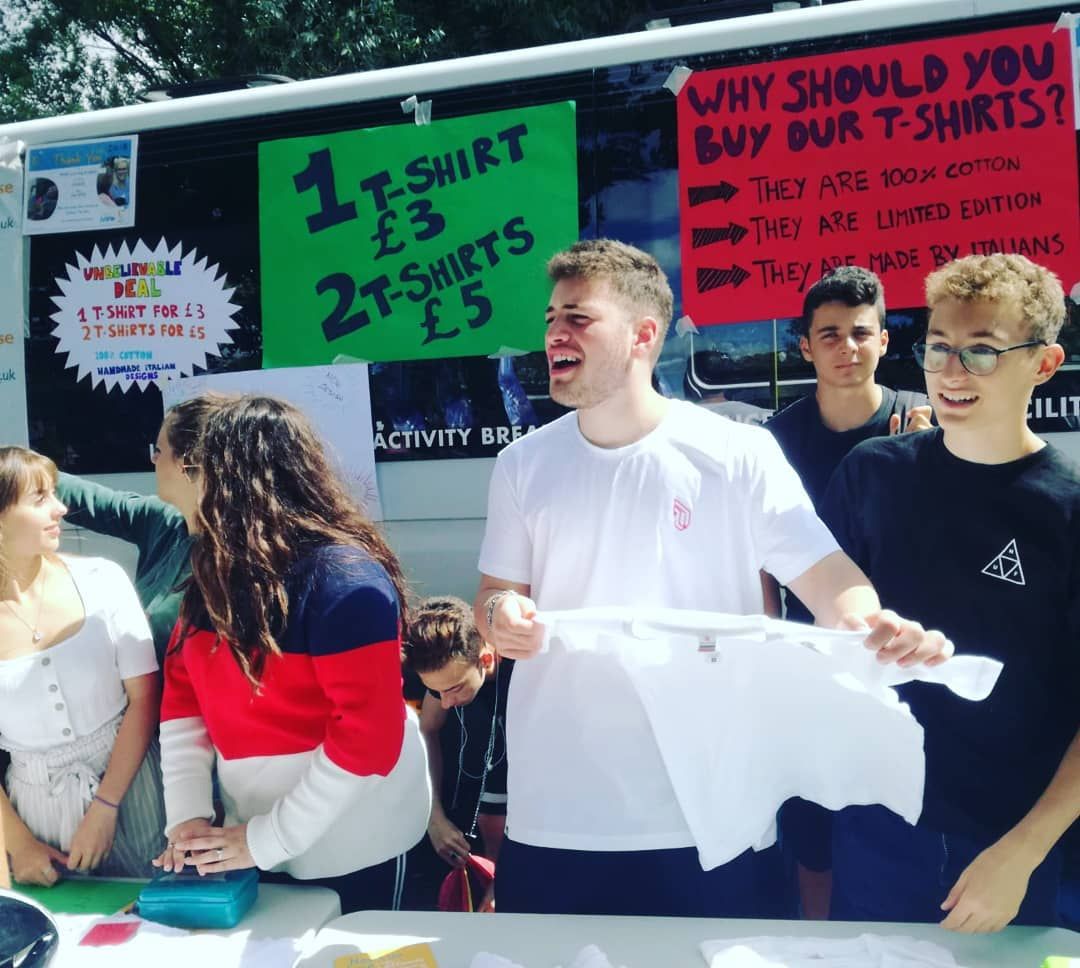 Eine Gruppe von Menschen steht vor einem Schild, auf dem steht, warum Sie unsere T-Shirts kaufen sollten