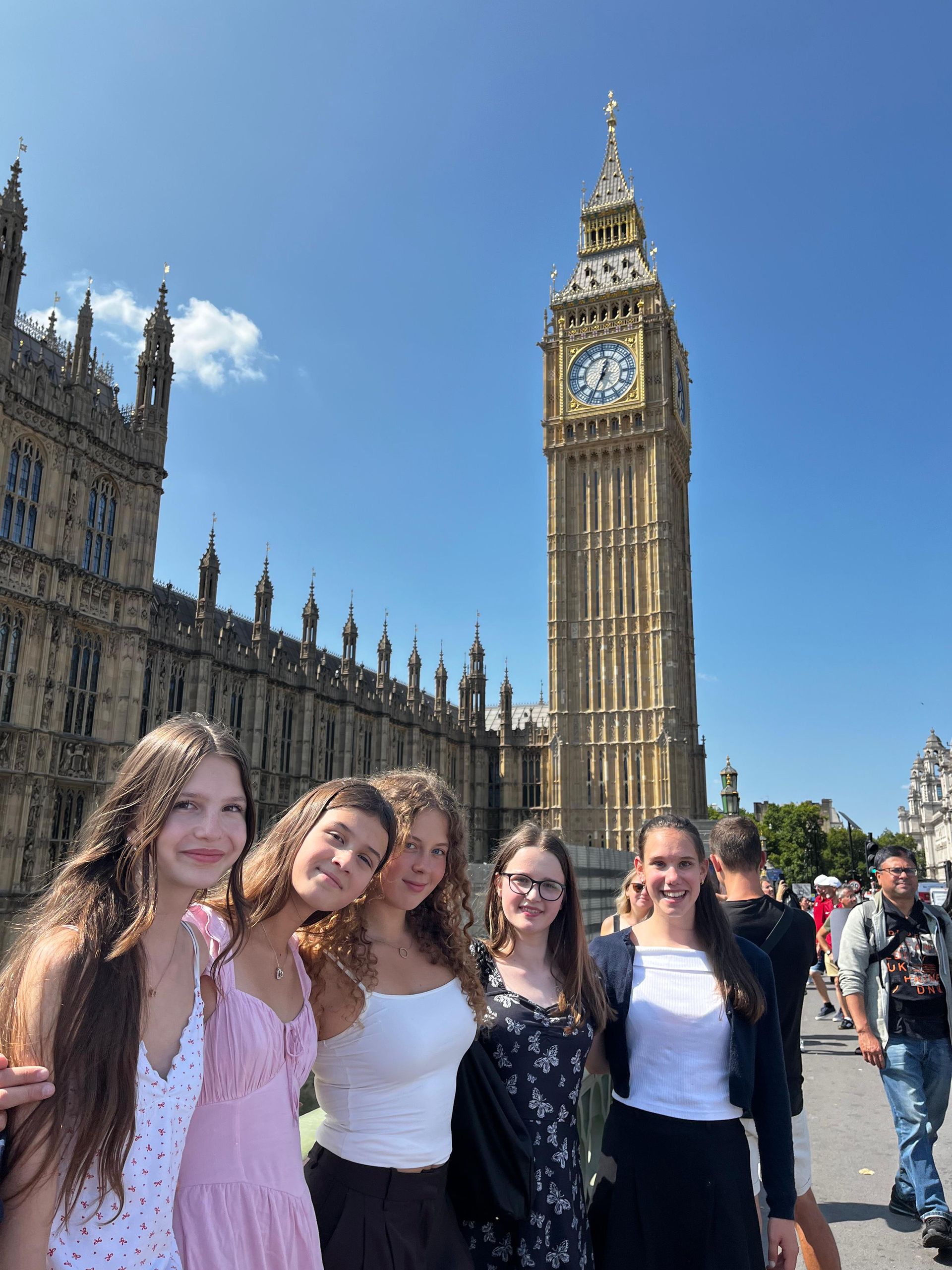 Fünf Personen posieren vor Big Ben und dem Parlamentsgebäude an einem sonnigen Tag.