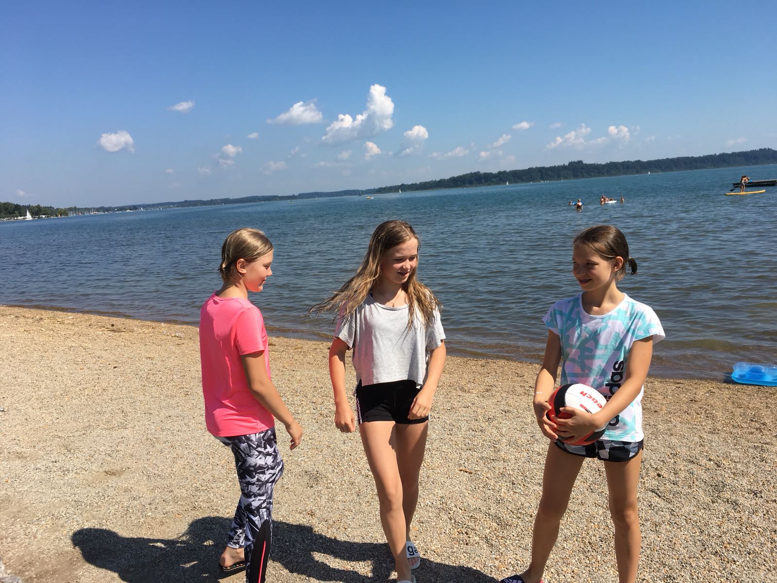 Drei junge Mädchen stehen am Strand und reden miteinander.