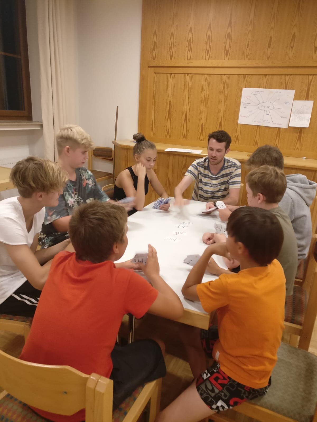 Eine Gruppe Kinder sitzt an einem Tisch und spielt Karten.