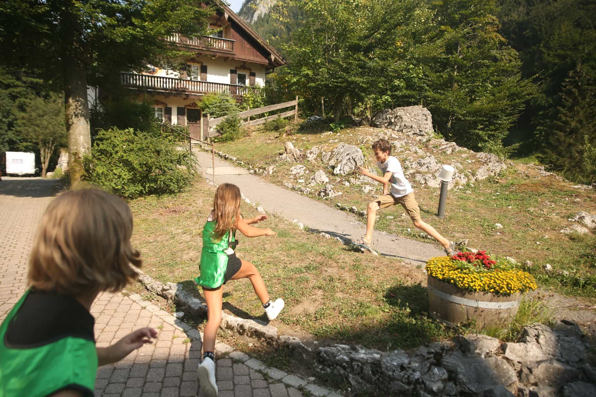 Ein Junge und ein Mädchen rennen einen Weg vor einem Haus entlang