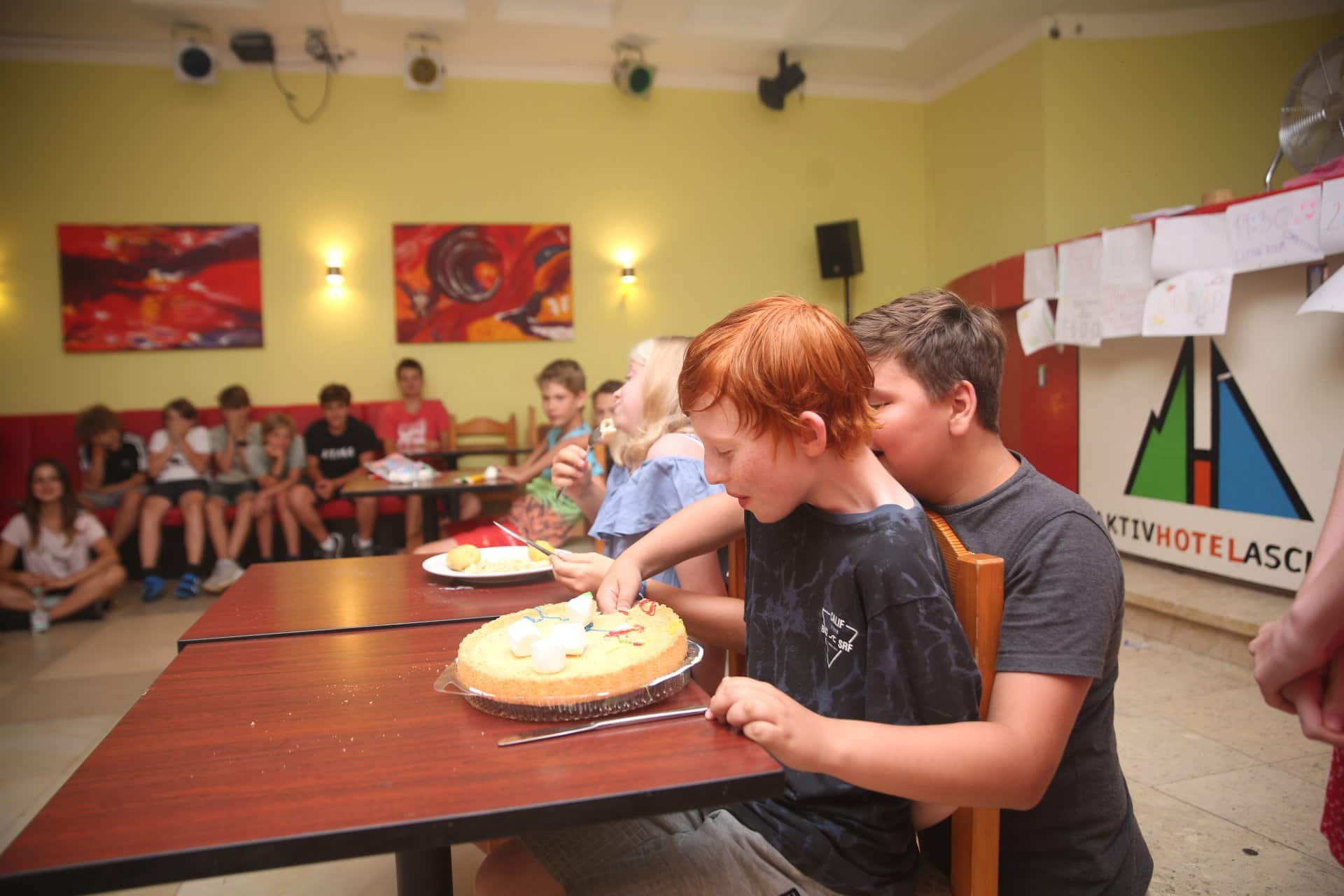 Eine Gruppe Kinder sitzt an einem Tisch und isst einen Kuchen