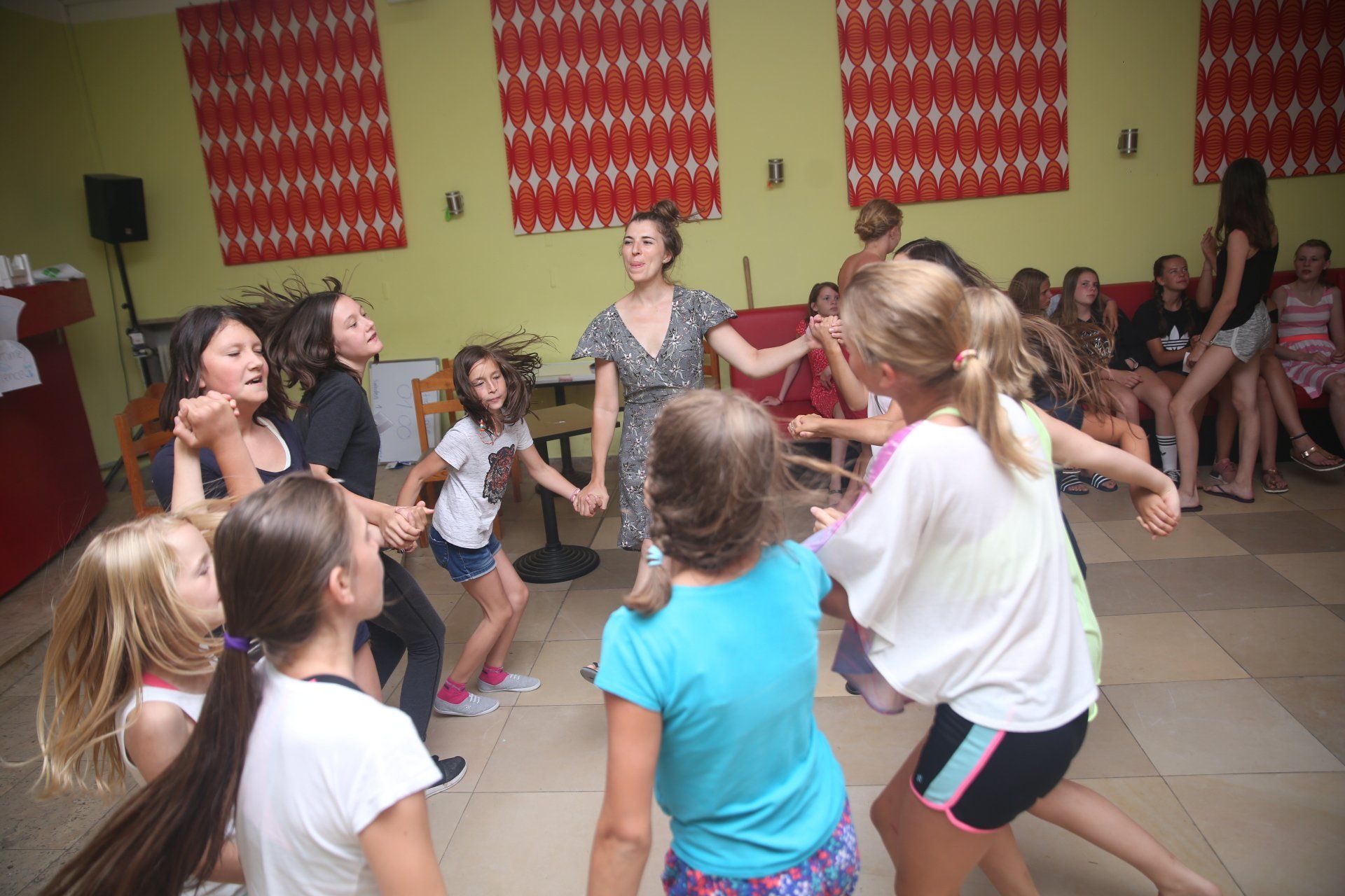 Eine Gruppe junger Mädchen tanzt im Kreis auf einer Tanzfläche.