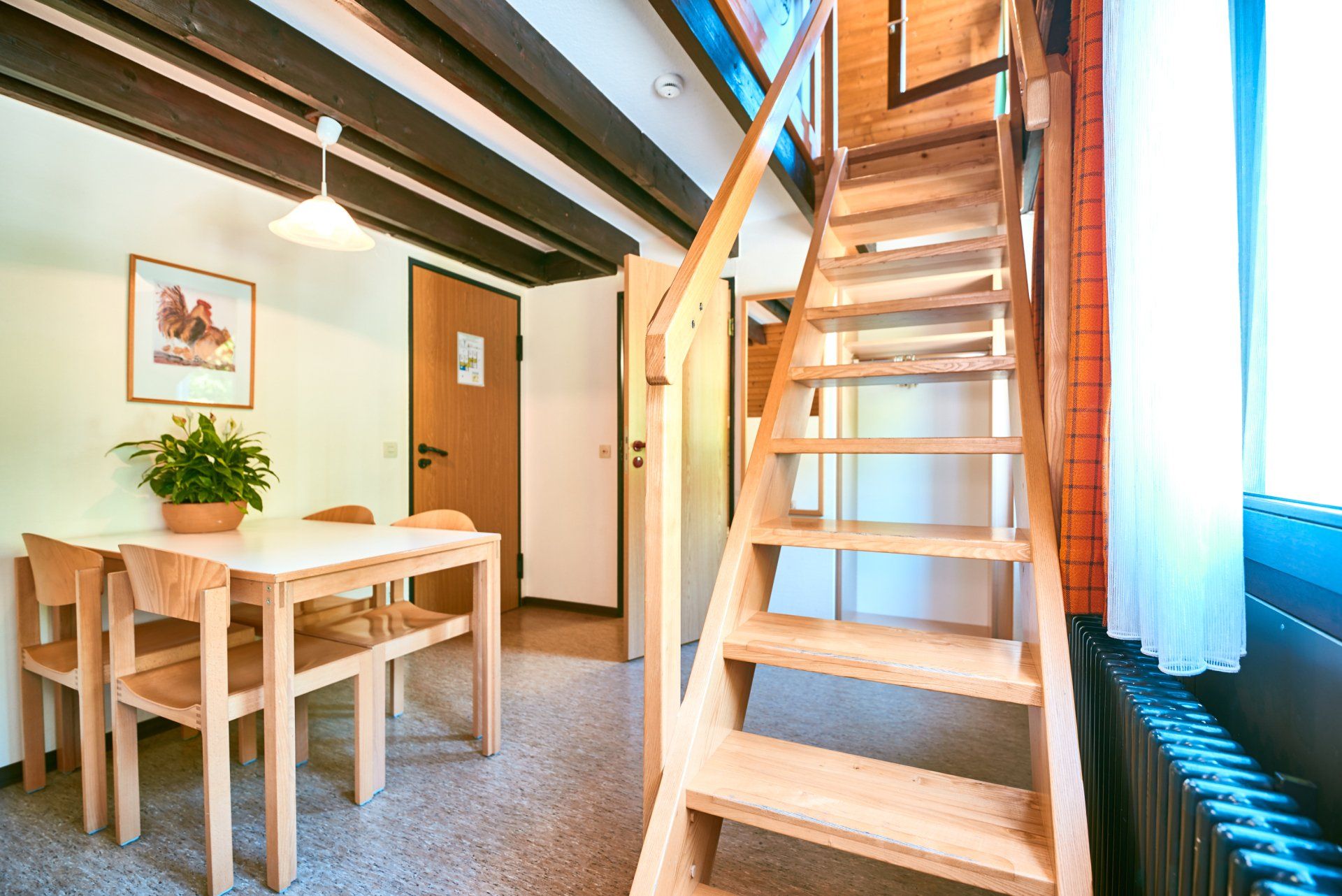 Interieur eines Zimmers mit Esstisch, Treppe und Tür. Naturholz und Beigetöne.