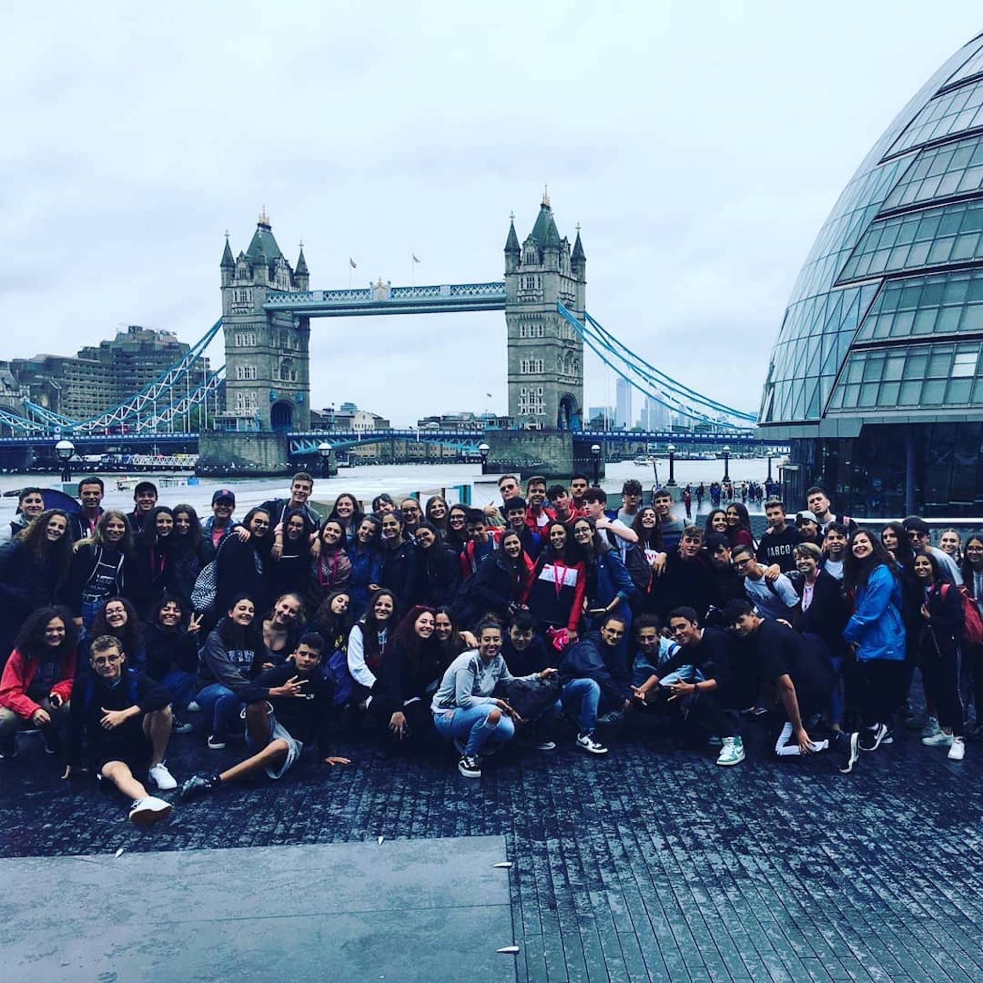 Eine große Gruppe von Menschen posiert vor einer Brücke für ein Foto.