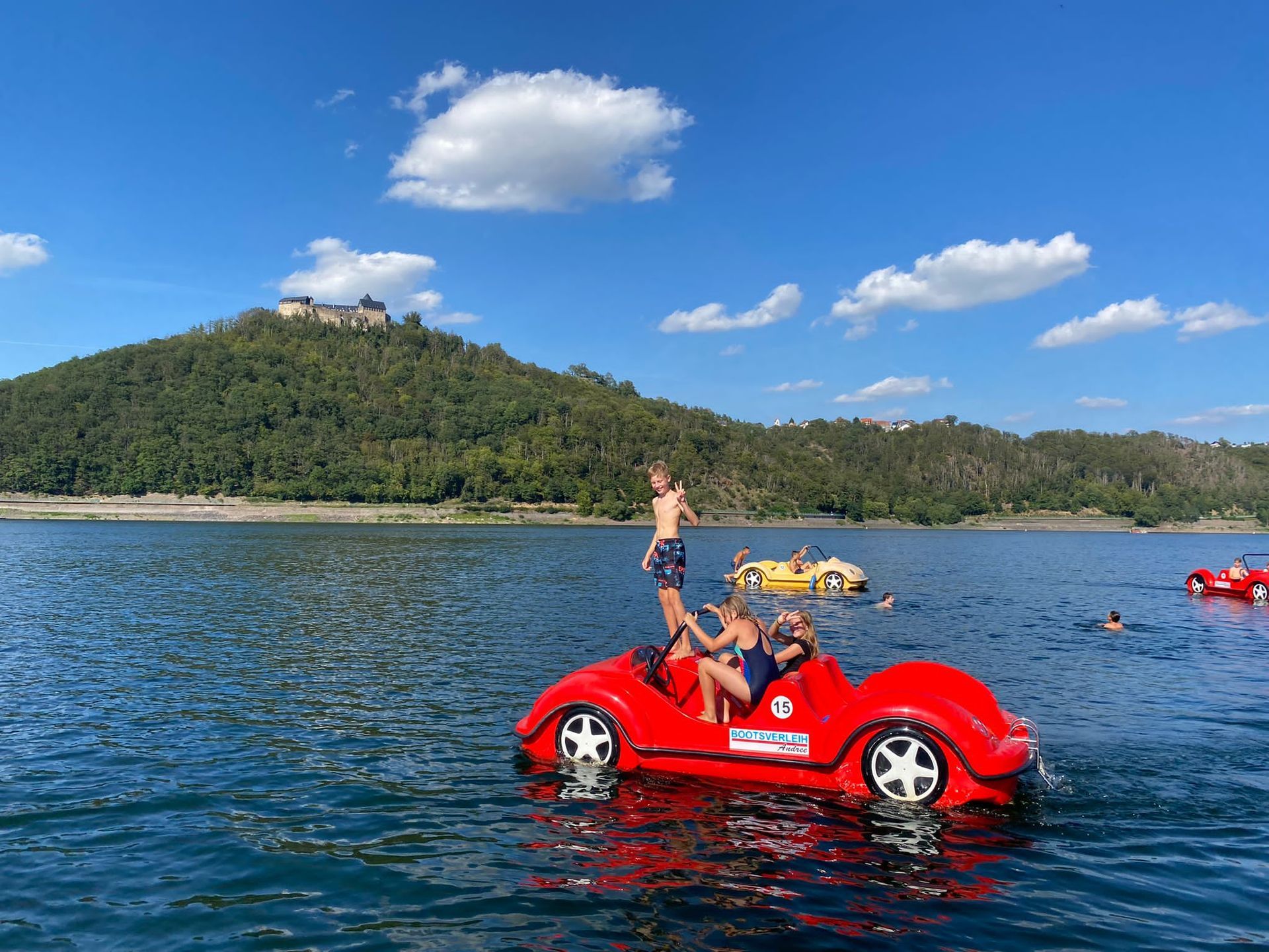 Eine Gruppe von Menschen fährt mit einem Tretboot auf einem See.