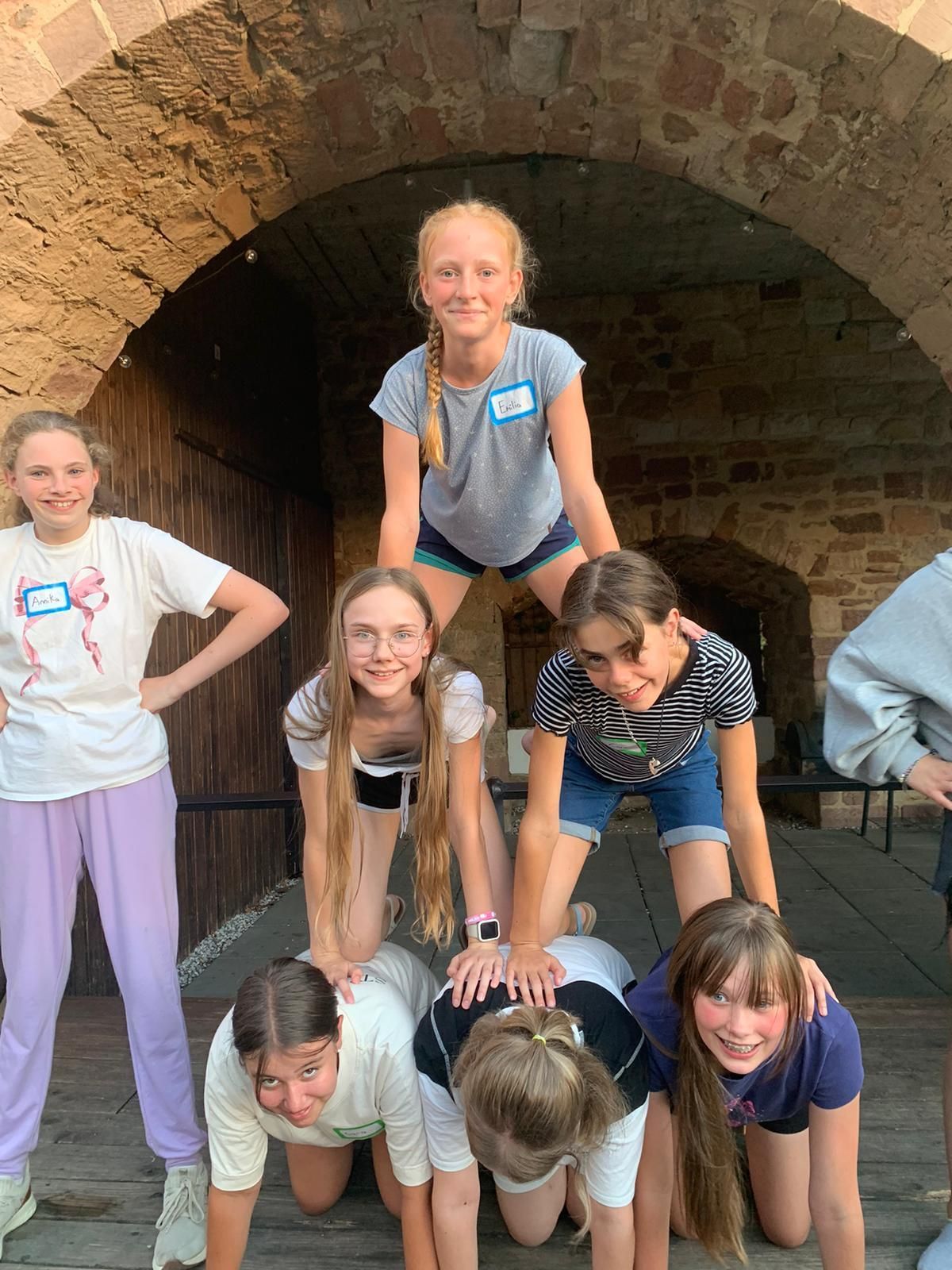 Eine Gruppe lächelnder Menschen bildet unter einem Torbogen eine Menschenpyramide.