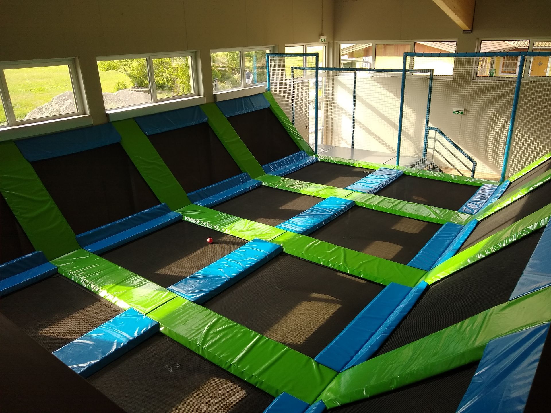 Indoor-Trampolinpark mit mehreren rechteckigen Trampolinen und Sicherheitspolsterung.