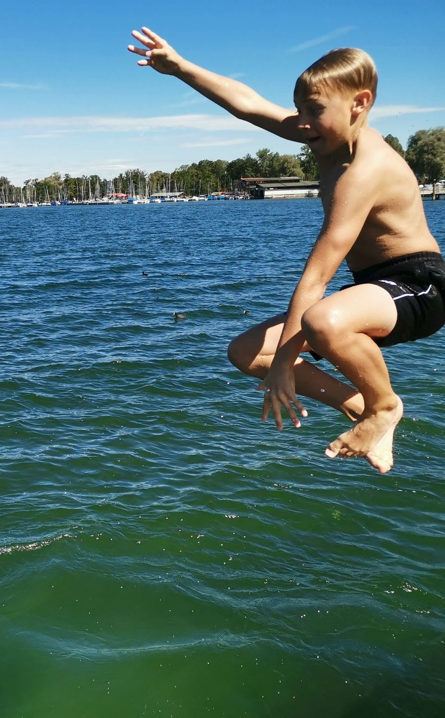 Ein kleiner Junge springt in ein Gewässer