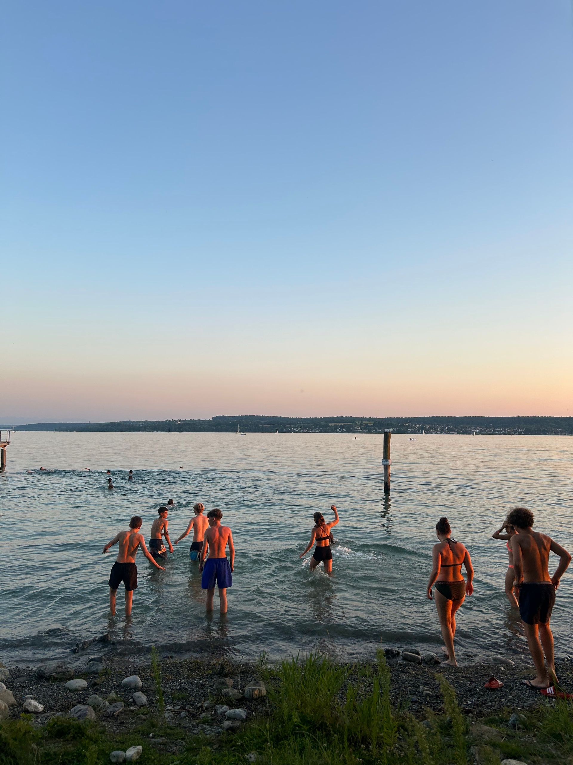 Menschen, die bei Sonnenuntergang in einem See oder im Meer ins Wasser waten.