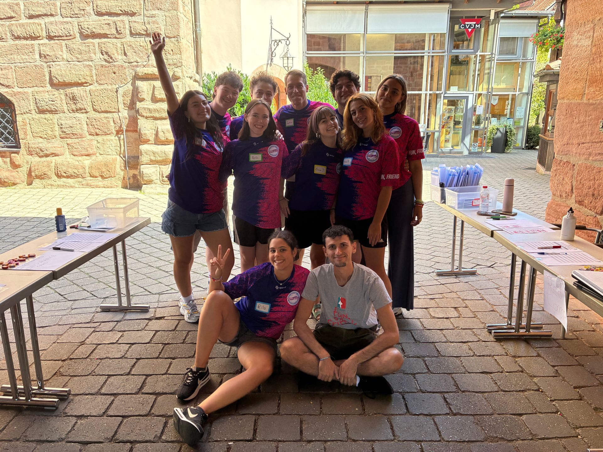 Eine Gruppe von Menschen in einheitlichen Hemden posiert im Freien in der Nähe von Tischen.