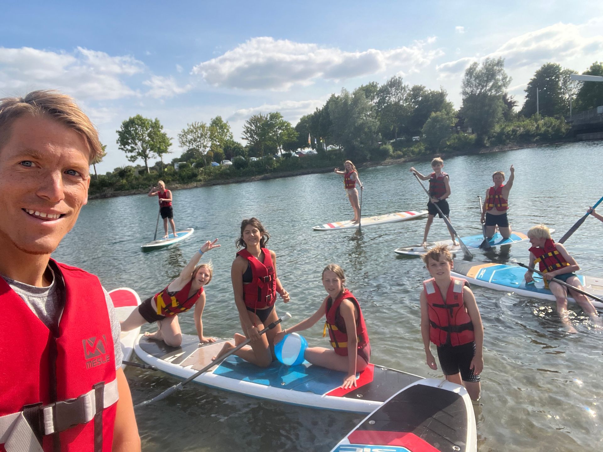 Eine Gruppe paddelt auf ruhigem Wasser; die Personen tragen Schwimmwesten, posieren und lächeln.