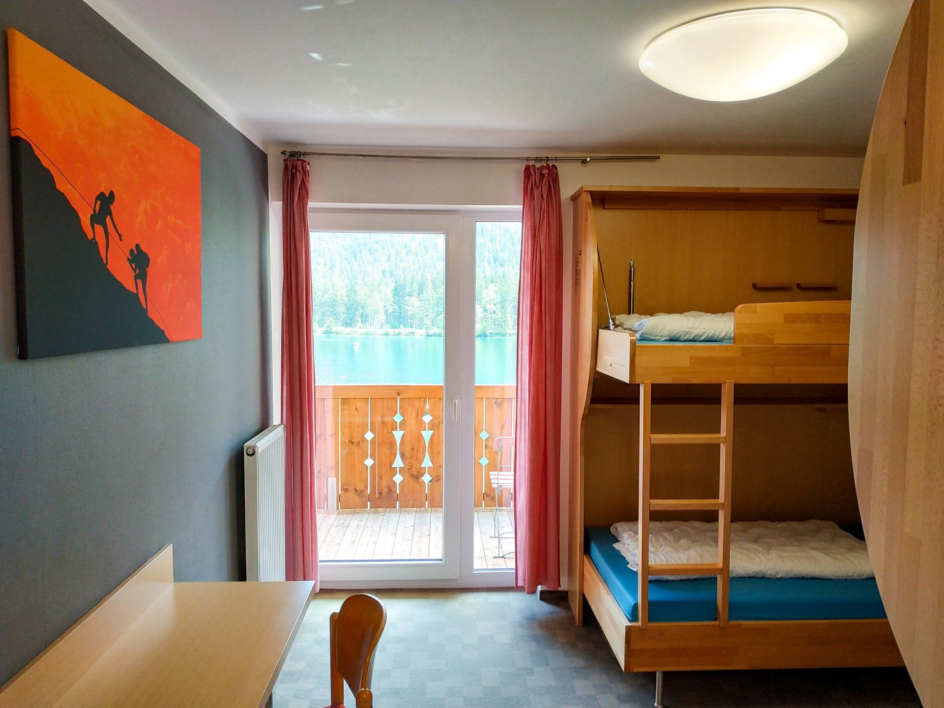 Innenraum mit Etagenbetten, Balkon und Kunst.