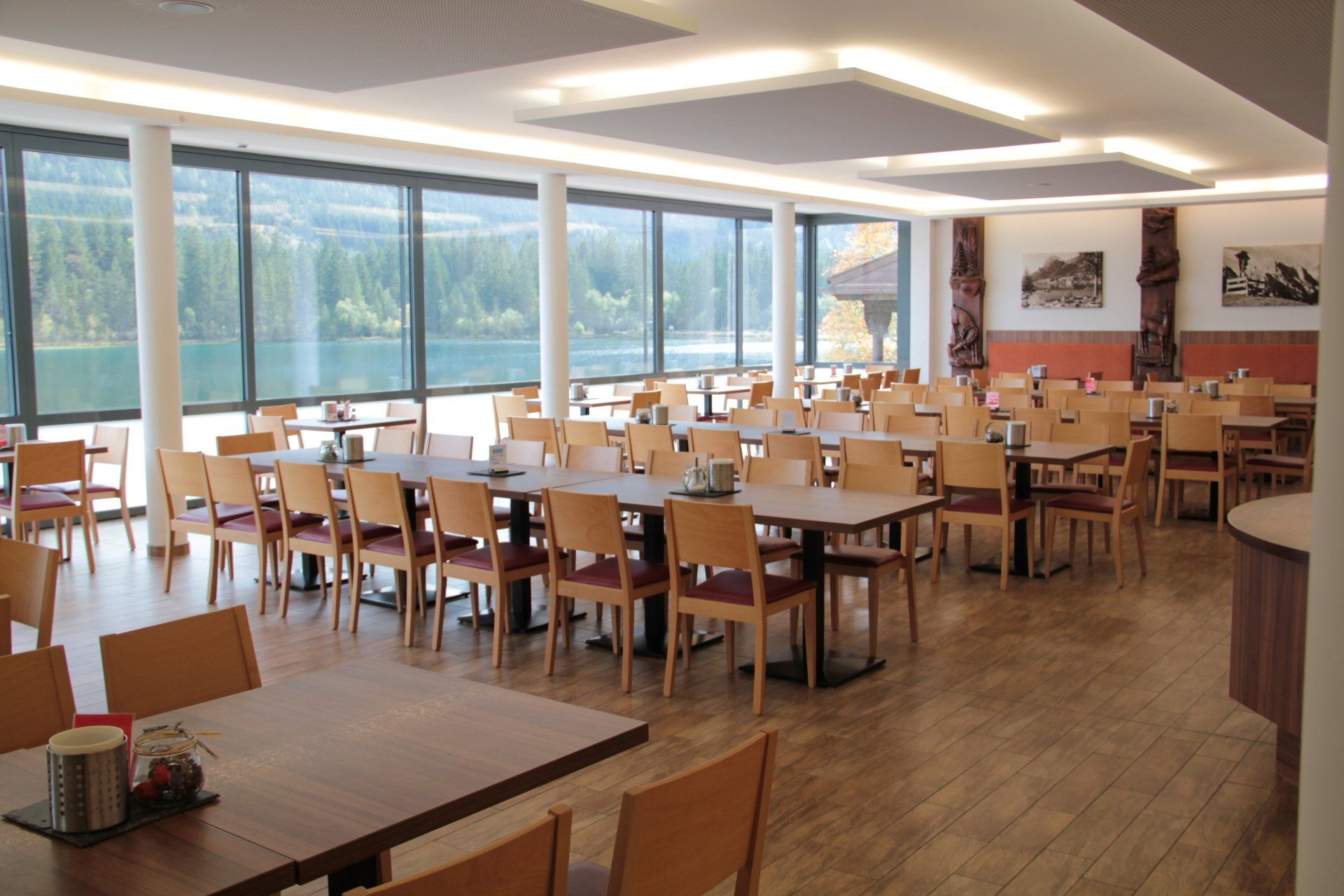 Esszimmer mit Tischen und Stühlen, große Fenster mit Seeblick.