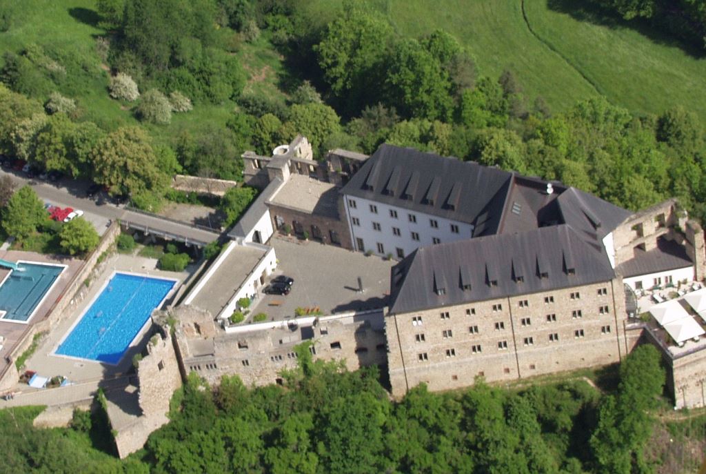 Luftaufnahme einer Schlossanlage mit Swimmingpool und üppiger grüner Umgebung.