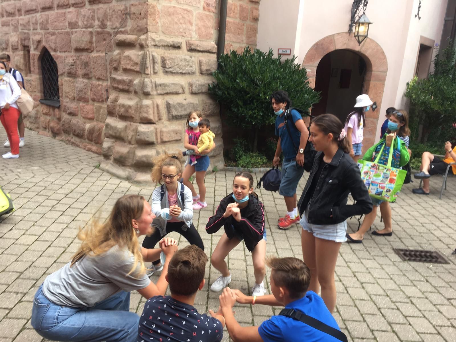 Eine Gruppe von Menschen, einige tragen Masken, versammelt sich im Freien, möglicherweise um ein Spiel zu spielen.