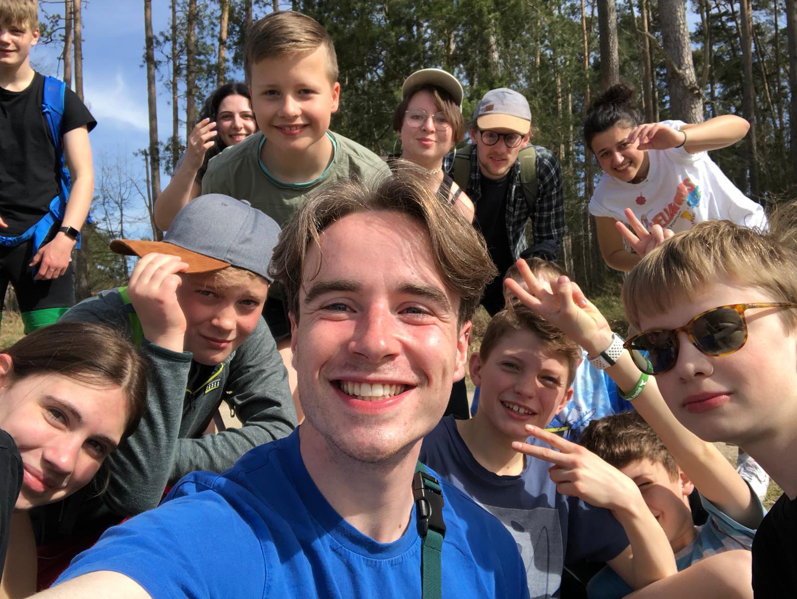 Eine Gruppe junger Leute posiert im Wald für ein Selfie.