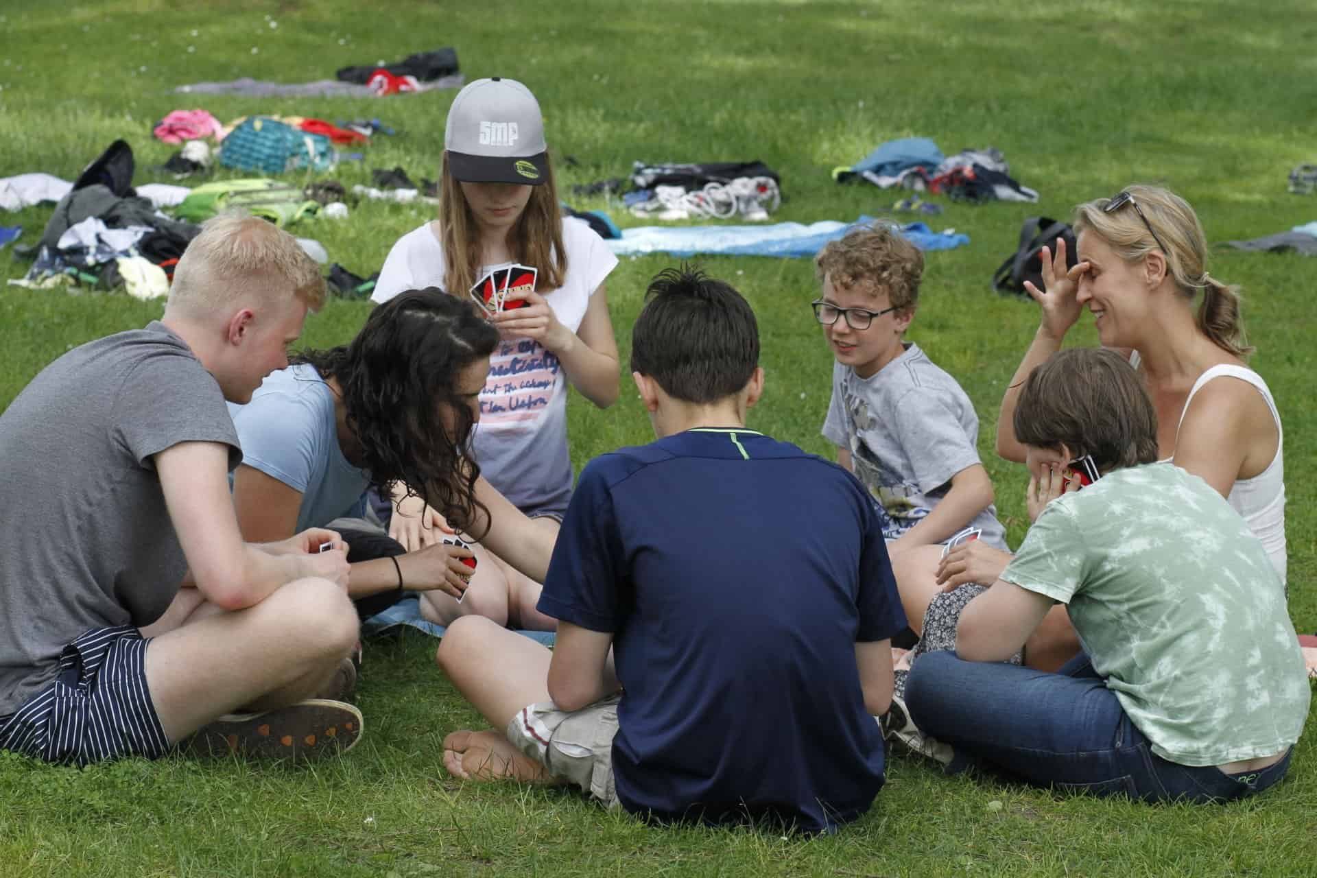 Eine Gruppe von Menschen sitzt im Kreis im Gras.