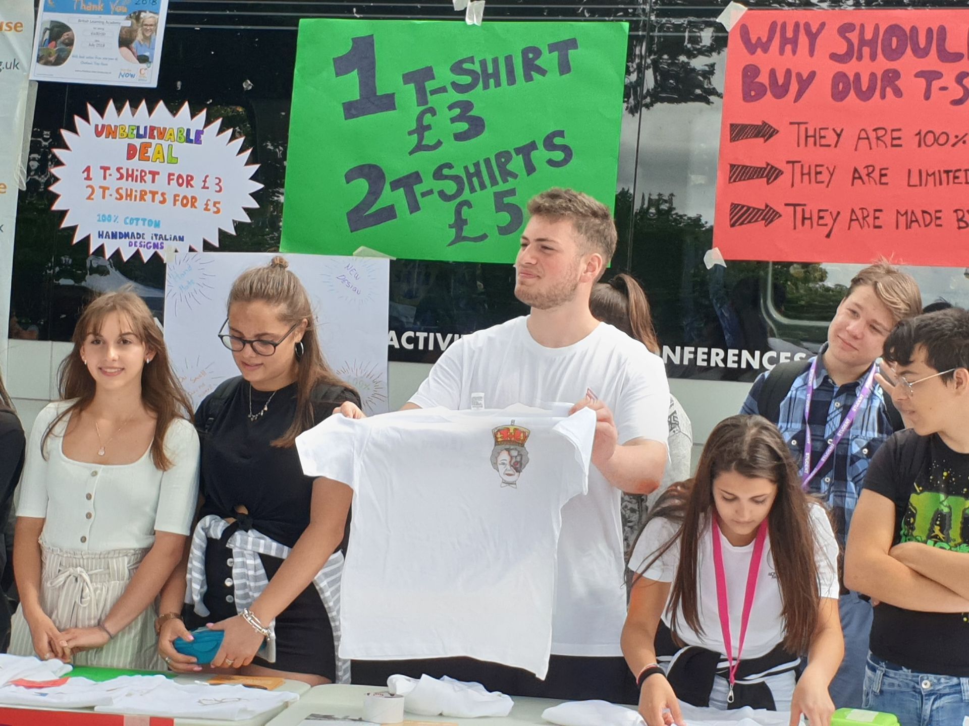 Eine Gruppe von Menschen steht um einen Tisch herum und hält T-Shirts zum Verkauf bereit.