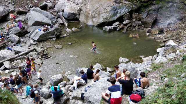 Eine Gruppe von Menschen sitzt auf Felsen in der Nähe eines Flusses.