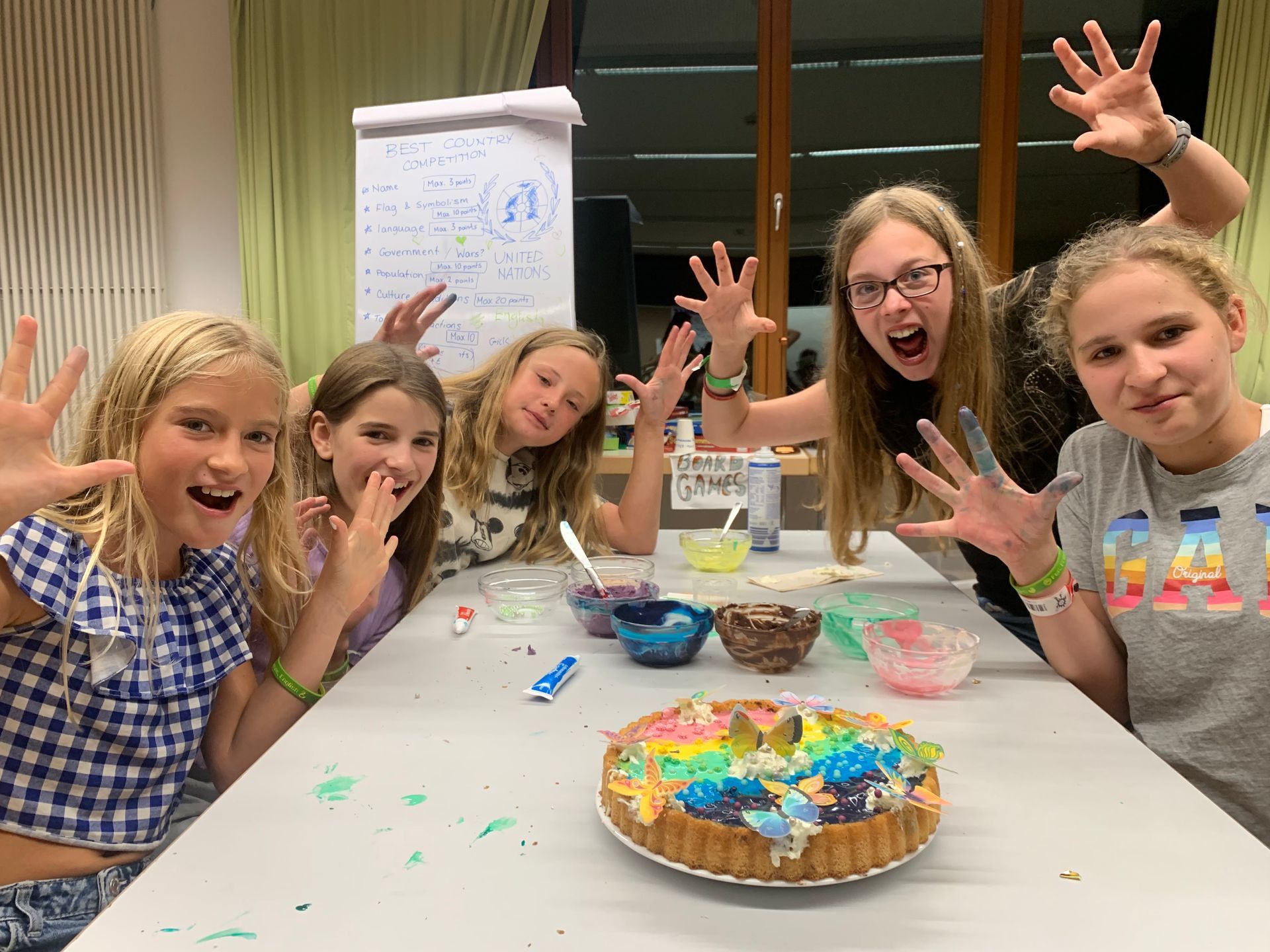 Eine Gruppe junger Mädchen sitzt an einem Tisch mit einem Kuchen darauf.