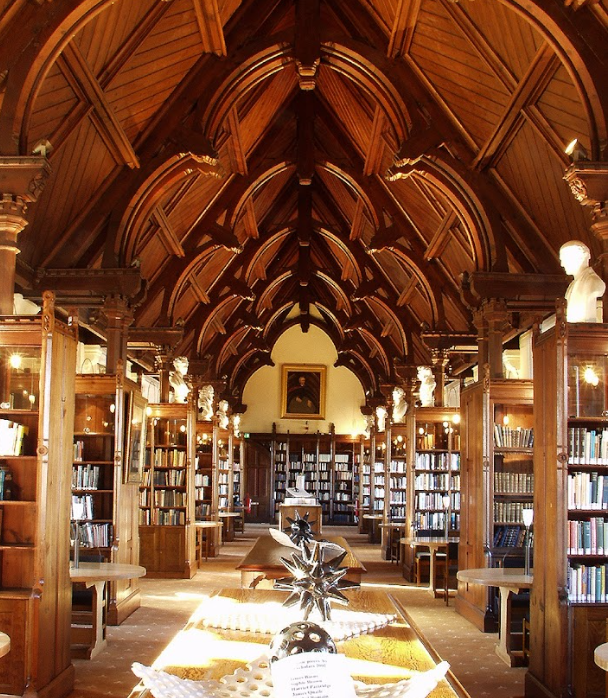 Bibliotheksinterieur mit hölzernem Bogendach, Bücherregalen und reich verzierter Decke.