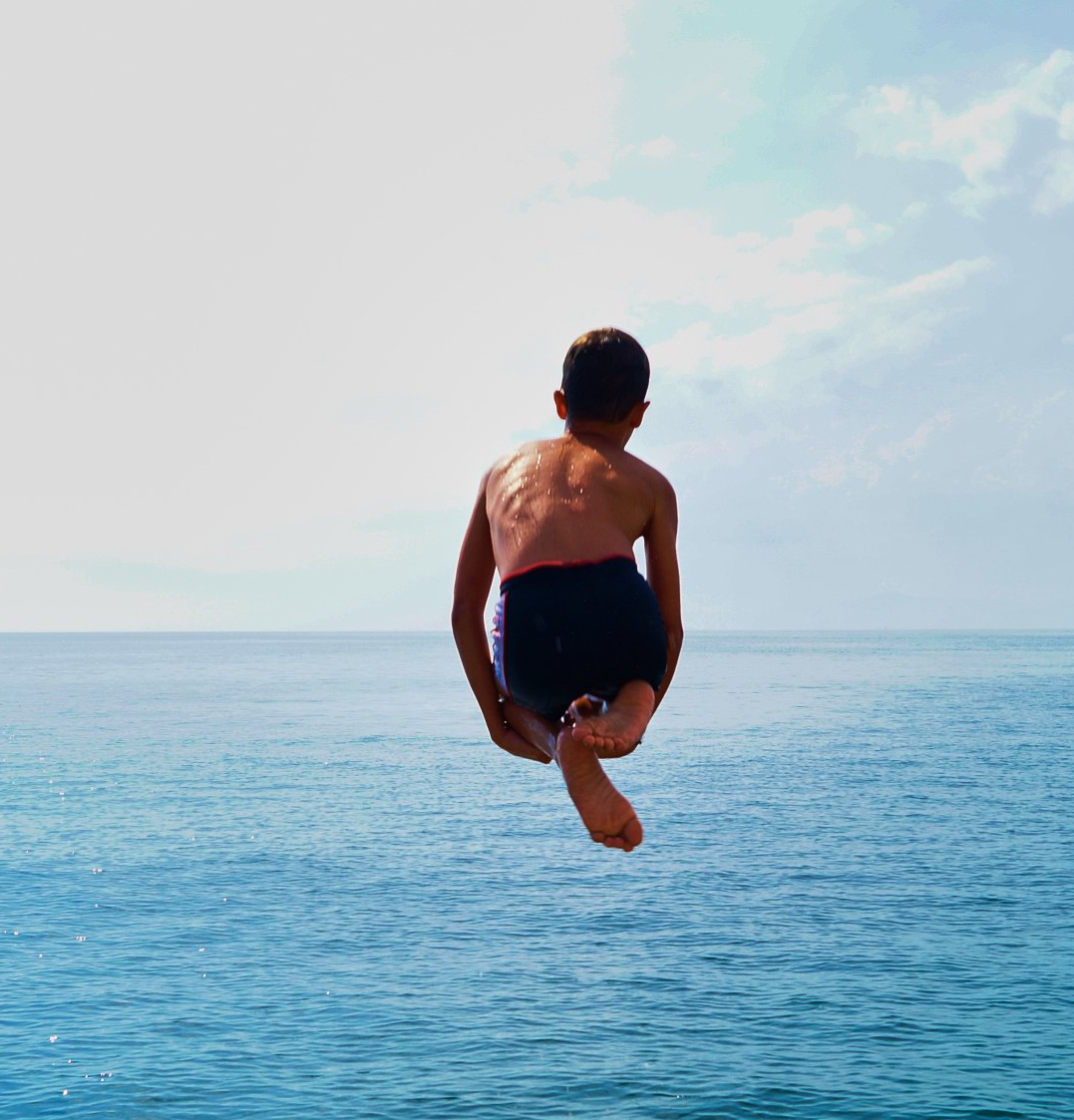 Ein kleiner Junge springt ins Meer