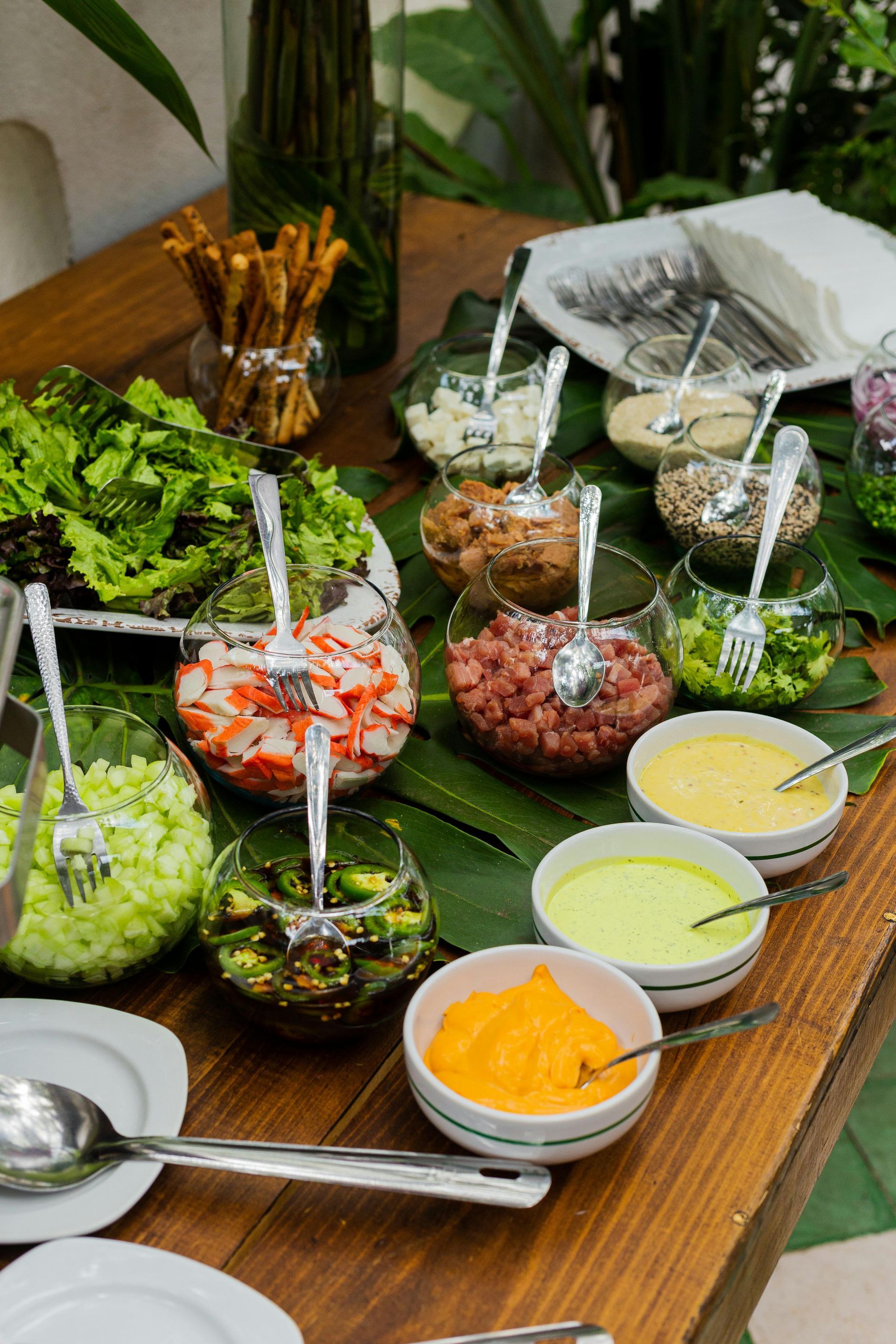 Buffet mit Salatzutaten und Dressings in Glasschüsseln.