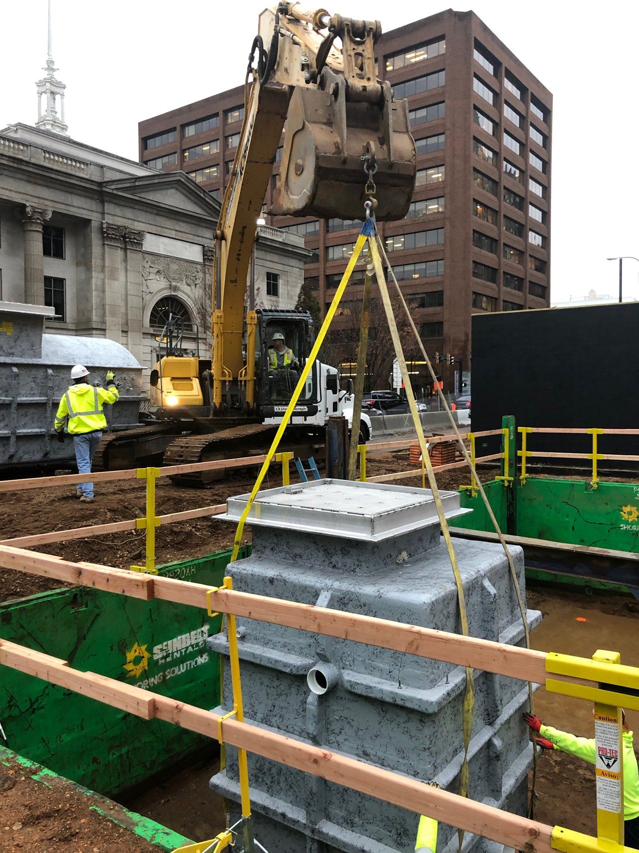A construction site with a large piece of equipment being lifted by a crane.