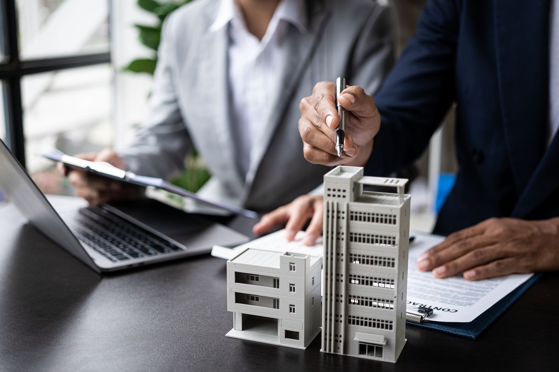 Business meeting with people reviewing a building model beside a laptop and documents