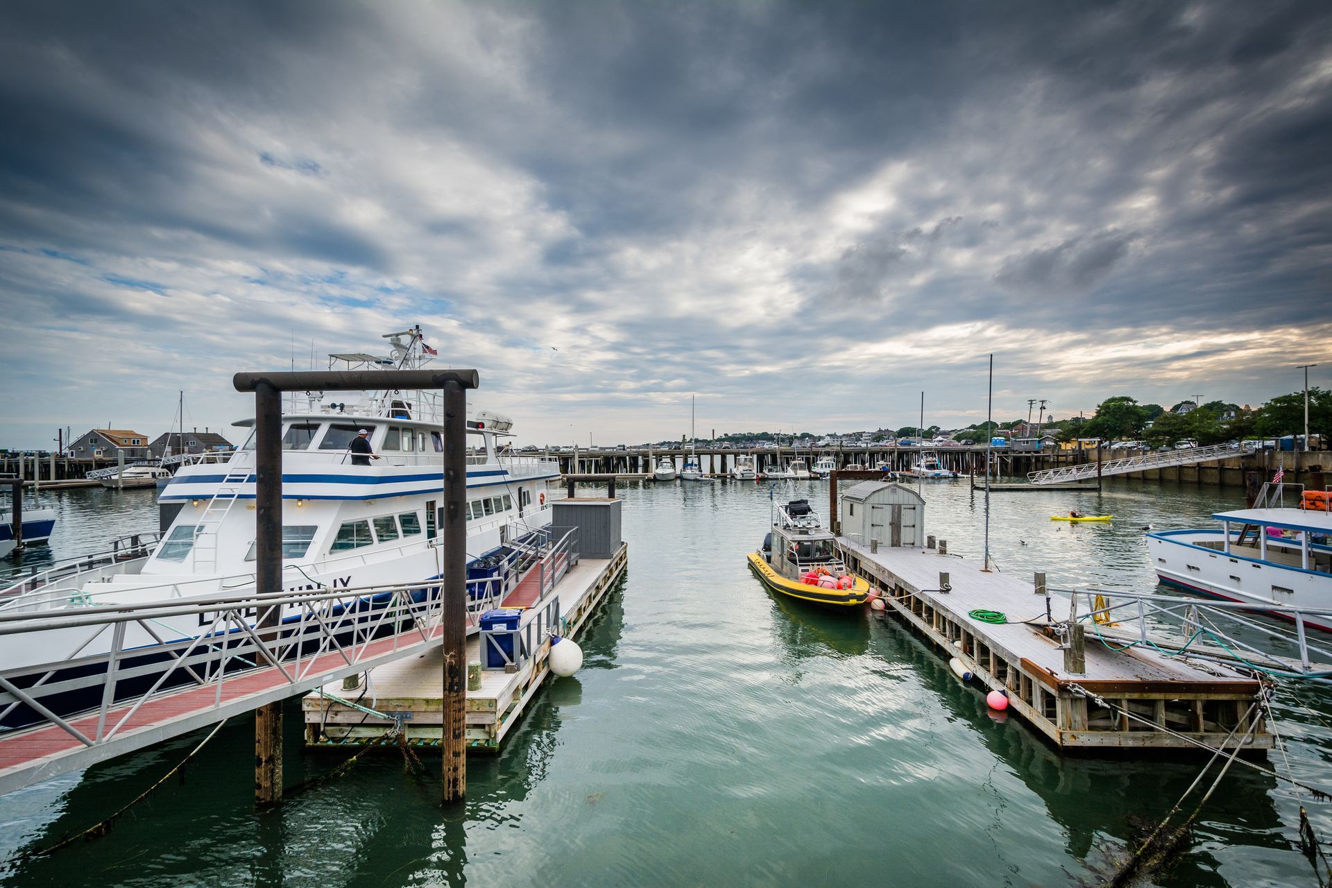 A group of boats are docked in a harbor on a cloudy day.