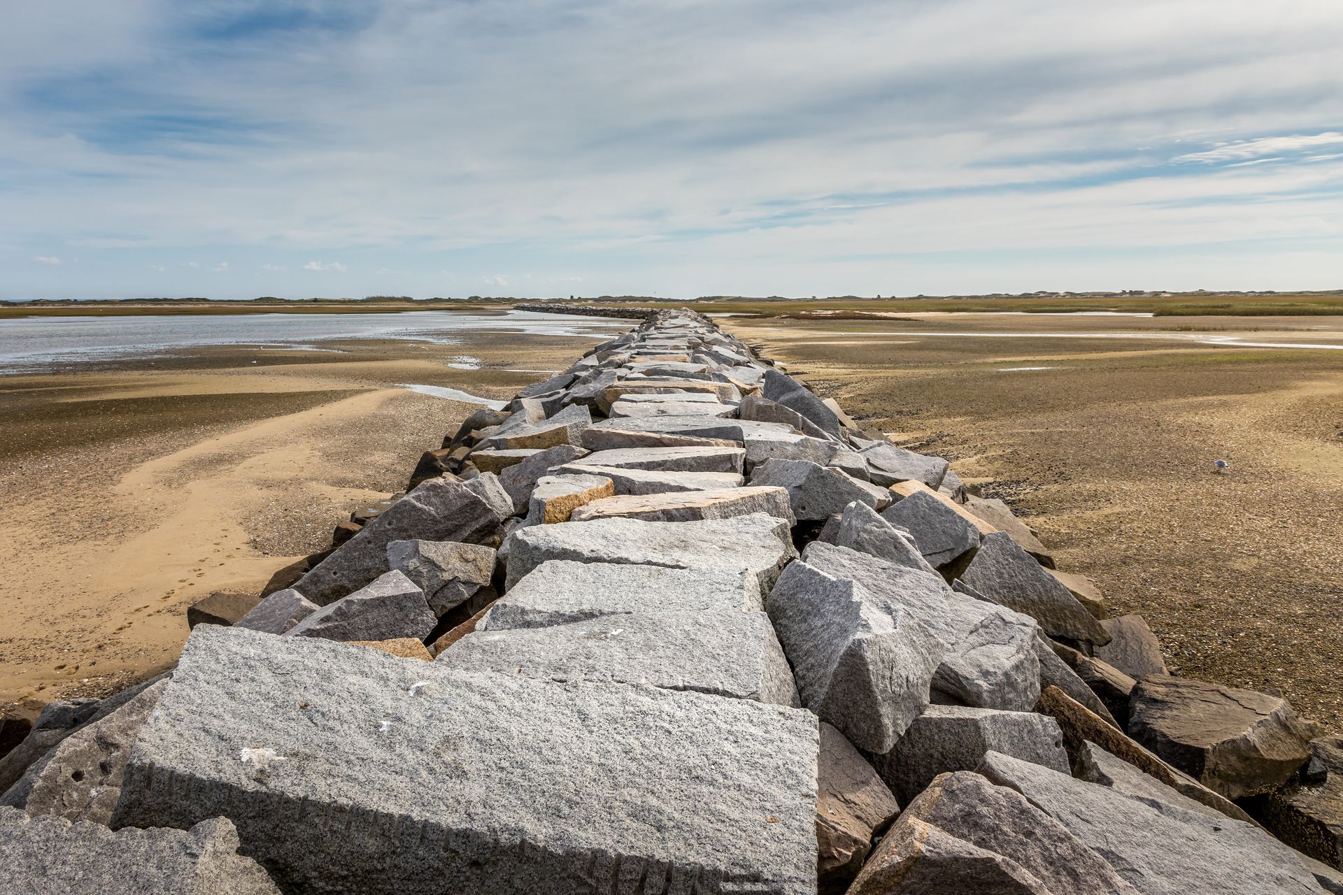 A row of rocks sitting on top of a sandy beach next to a body of water.