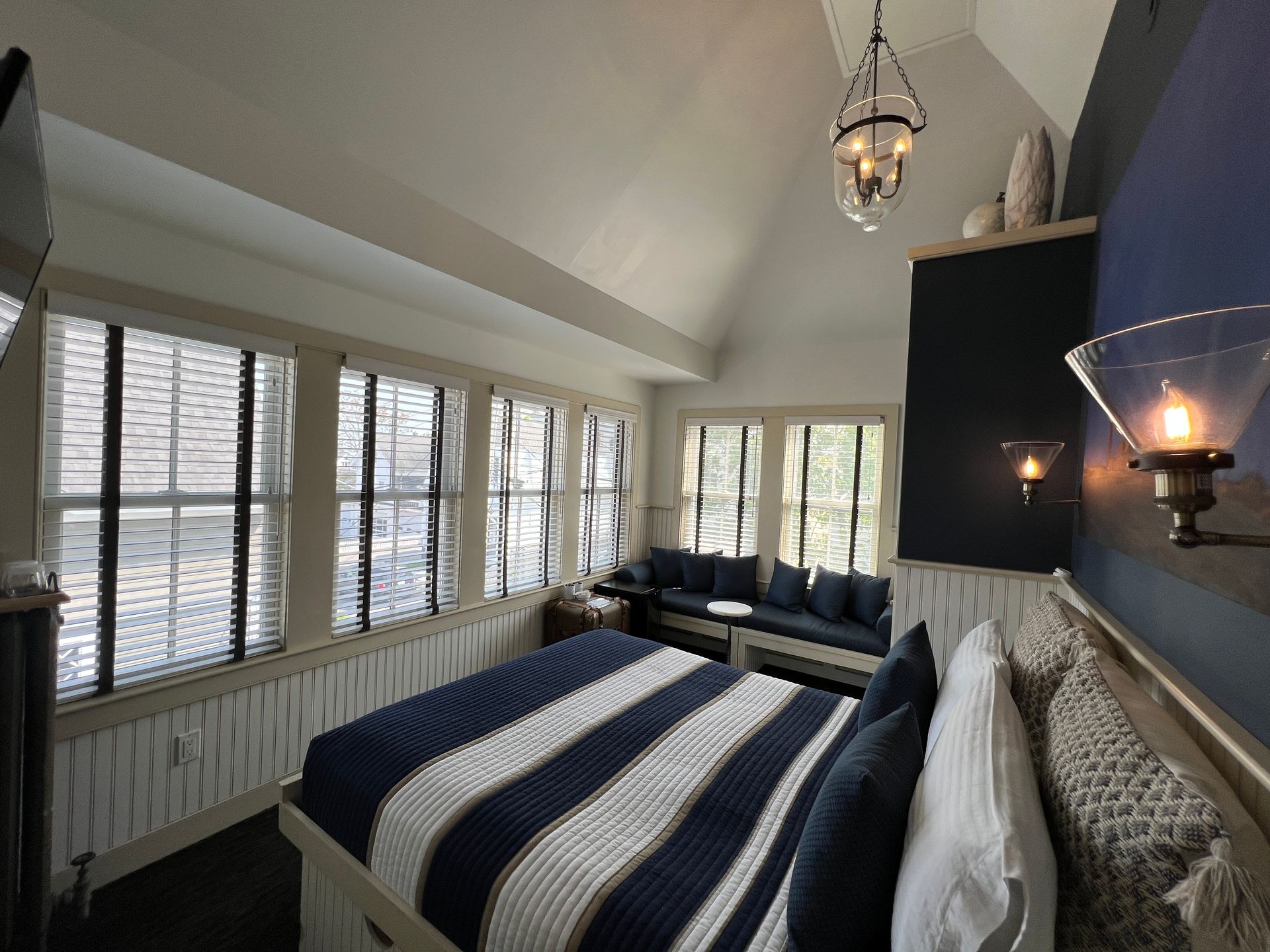 Blue guest room with queen bed, high ceilings, and 6 windows.