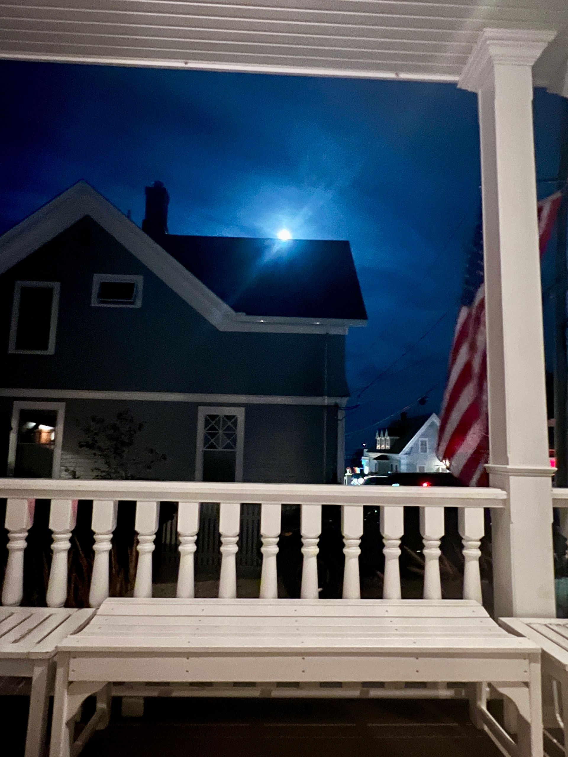 Moon setting over a roof top and porch.