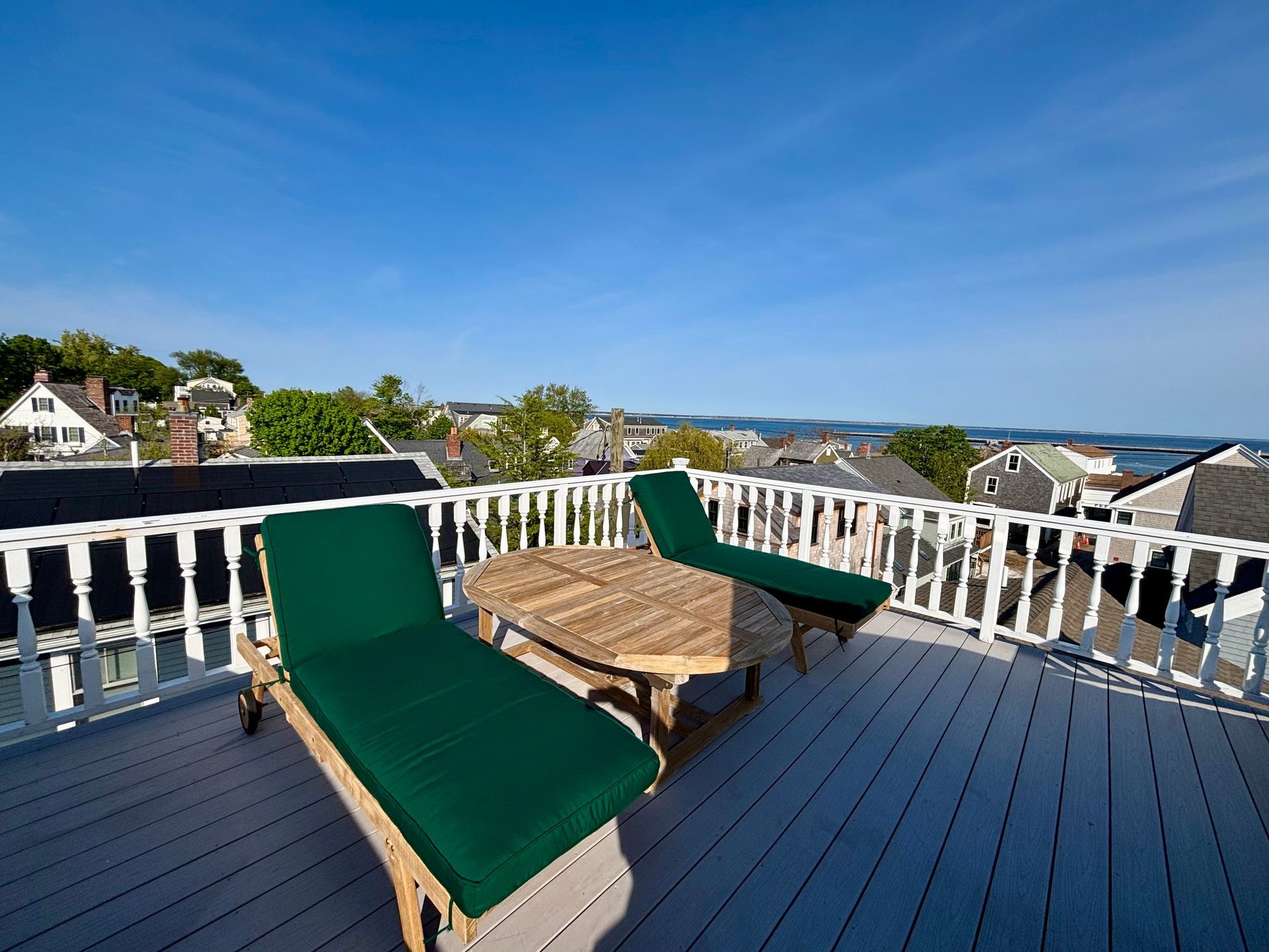 Exterior picture of the roof deck with two lounge chairs, table, and bay views