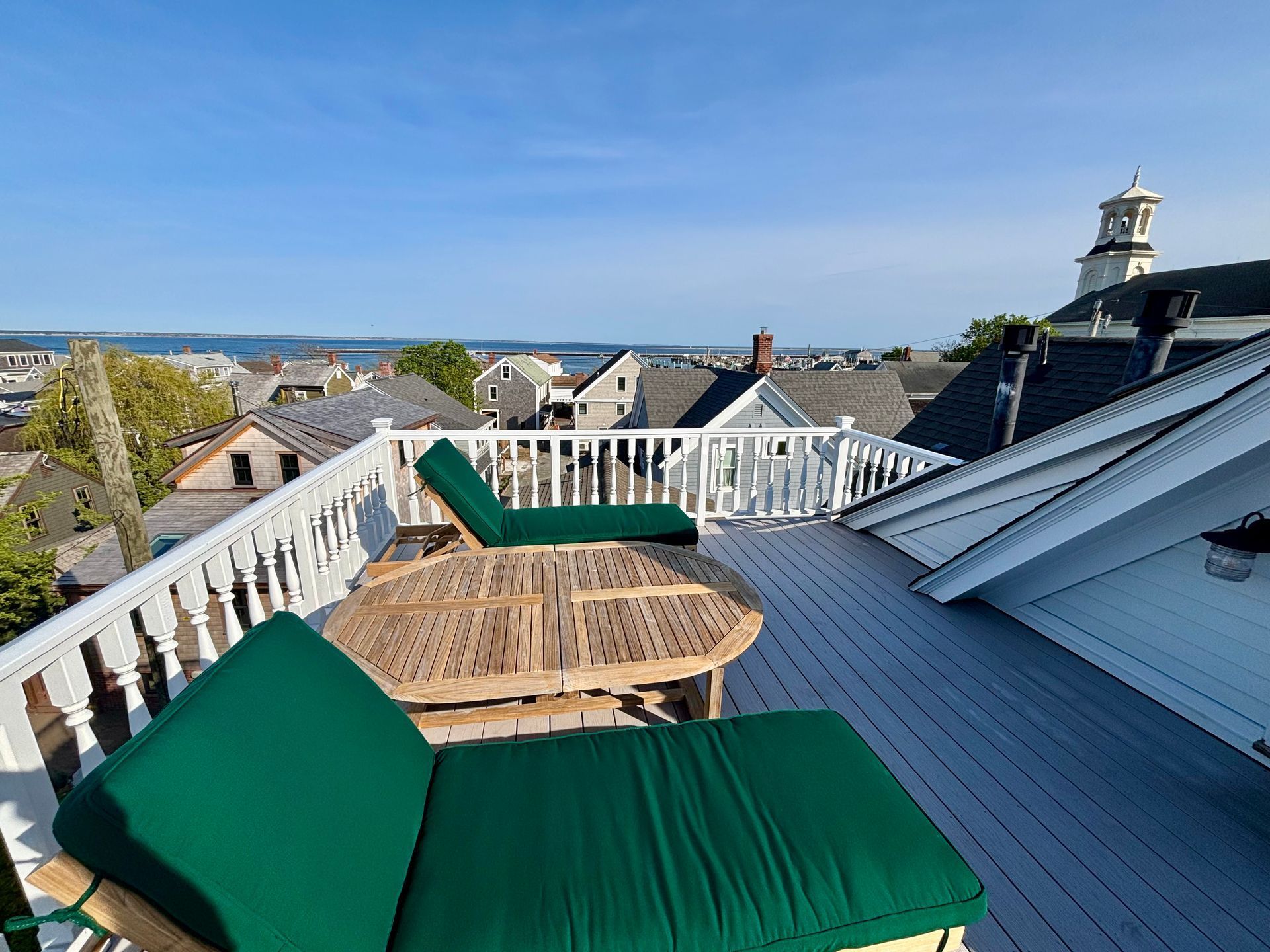 Roof deck at the White Porch Inn boutique hotel with chairs, table, and water views.