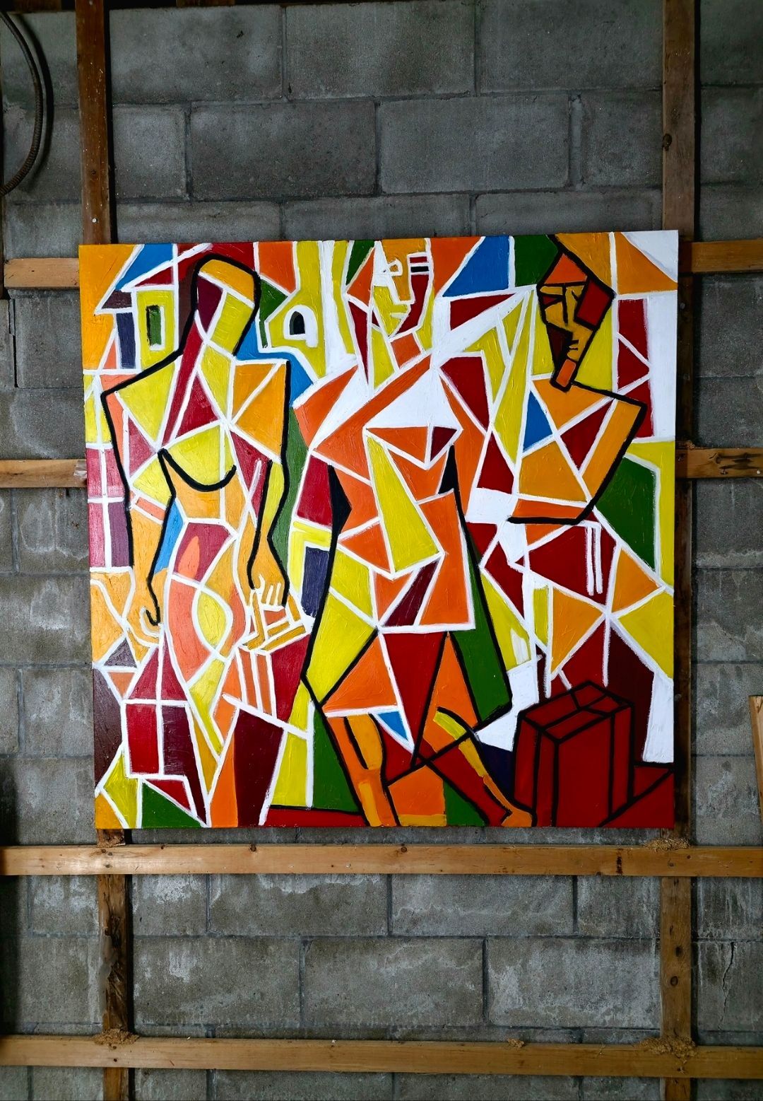 Abstract geometric mural in red, yellow, orange, and white on a gray cinderblock wall