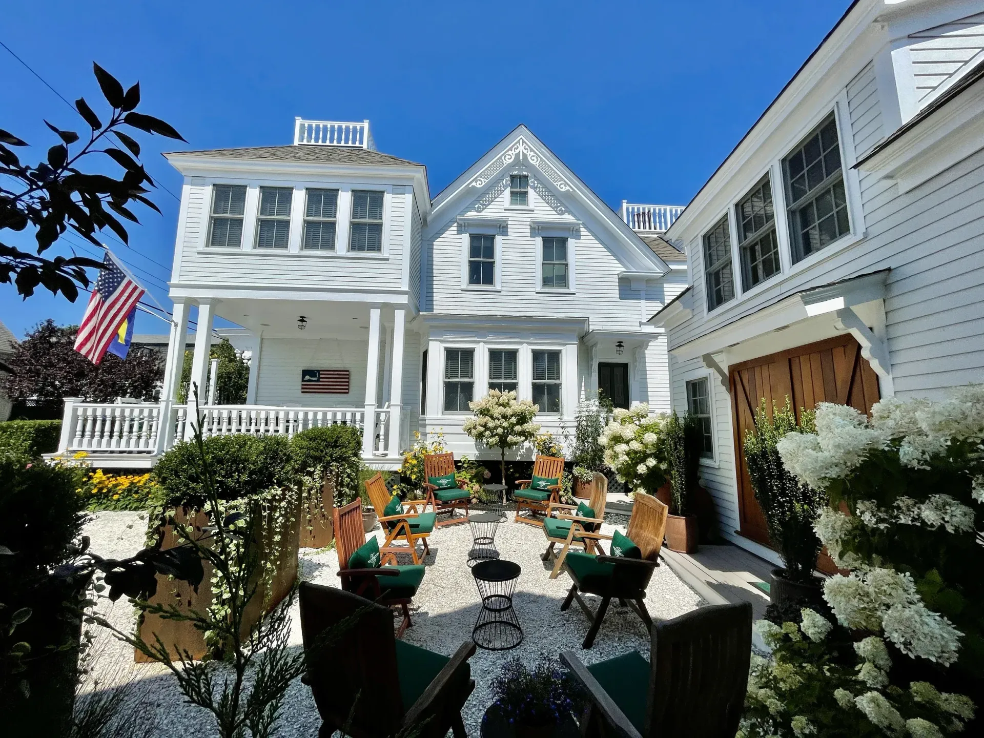 Exterior picture of the the main house, carriage house, garden, and porch at the White Porch Inn Art Hotel