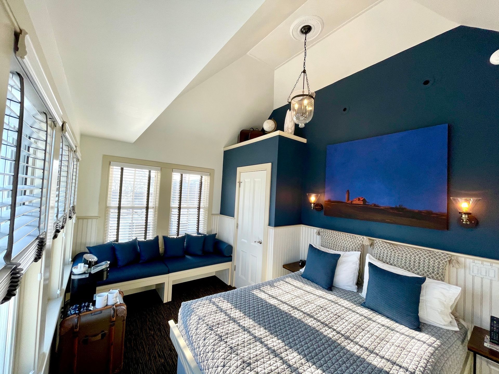 A bedroom with a bed , couch , and painting on the wall.