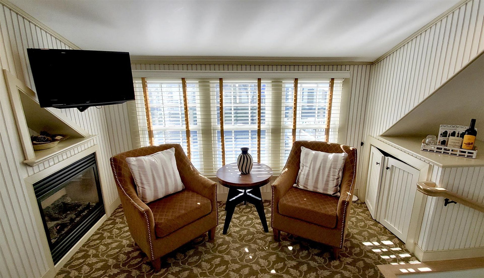 interior room picture of two chairs and a table in front of 3 windows.