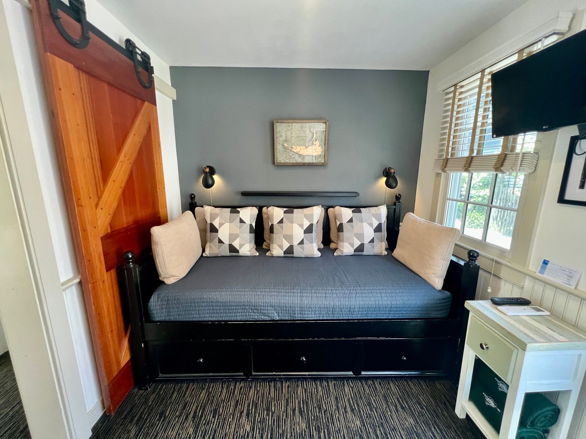 Interior room picture with a day bed, wooden barn door, and a window.