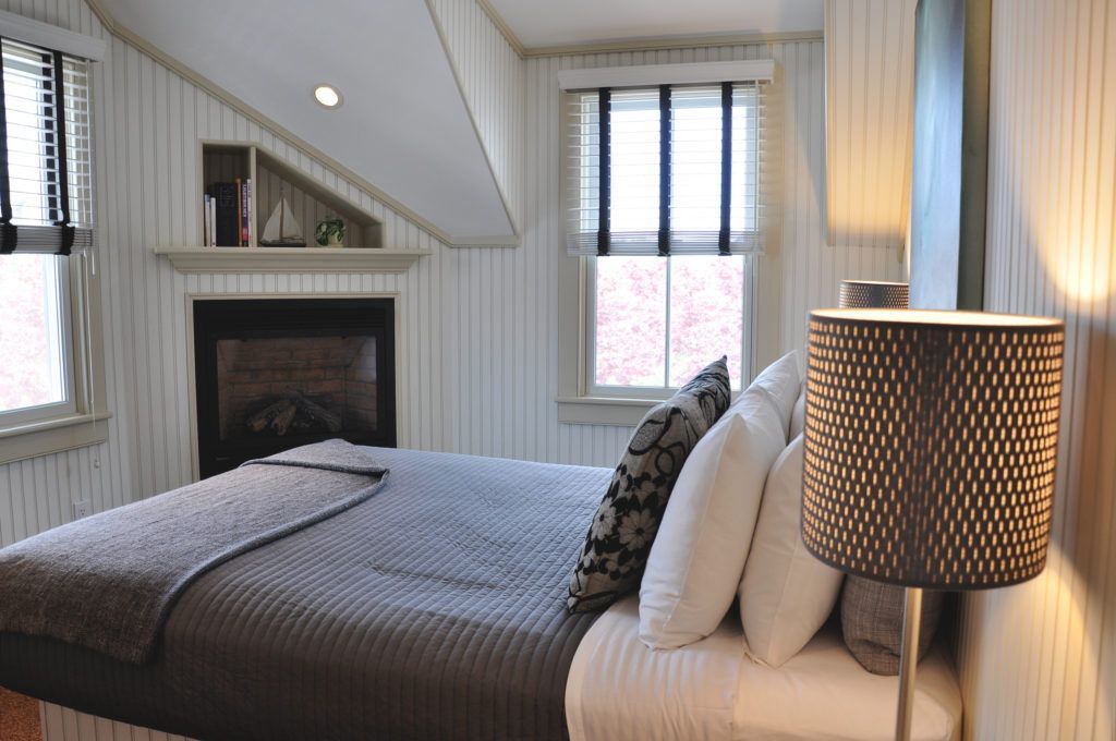 A bedroom with a bed a lamp and a fireplace