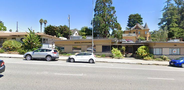 A couple of cars are parked on the side of the road in front of a building.