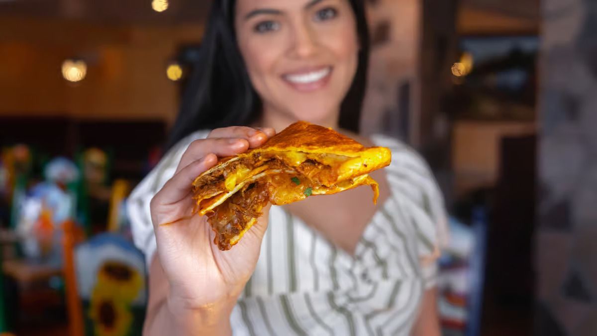 A woman is holding a slice of pizza in her hand.
