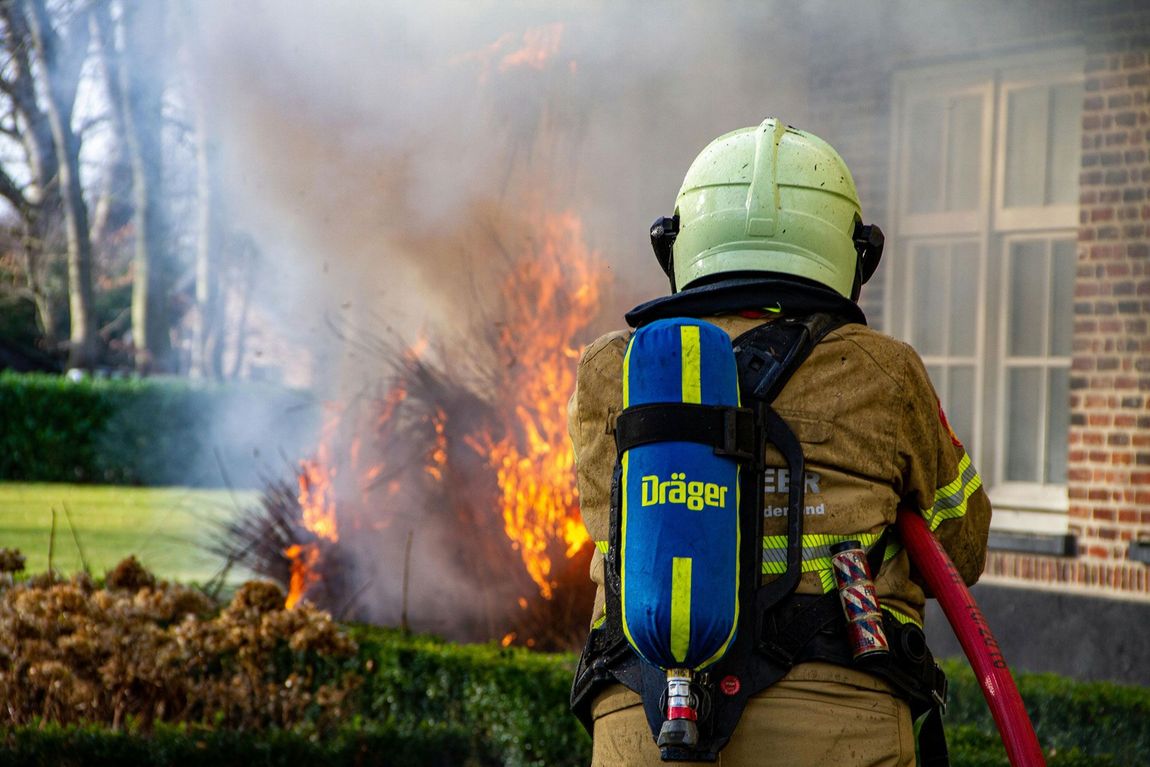 A fireman is standing in front of a large fire.